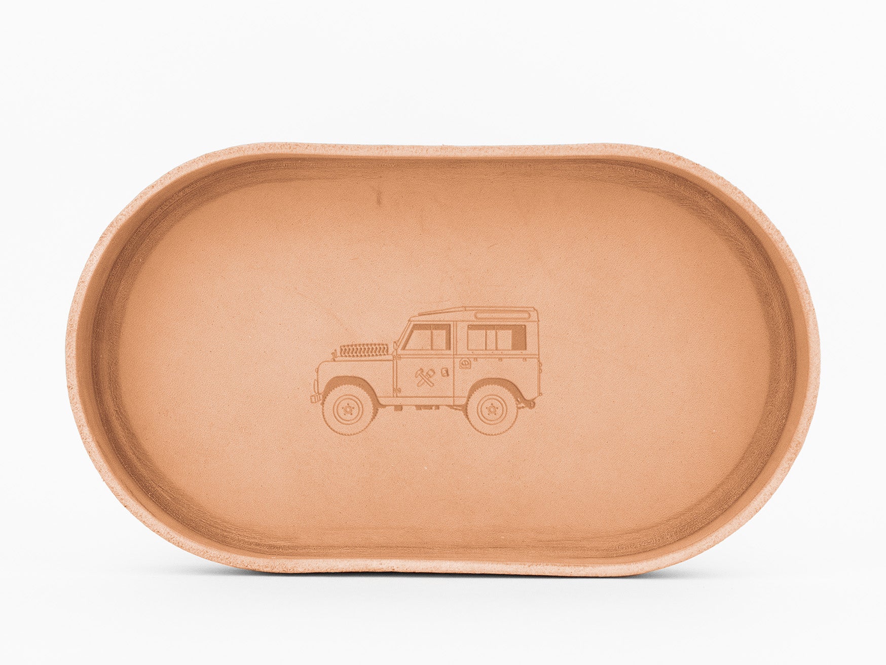 A oval-shaped, natural colored leather  tray with an embossed image of a classic off-road vehicle in the center, displayed on a white background.
