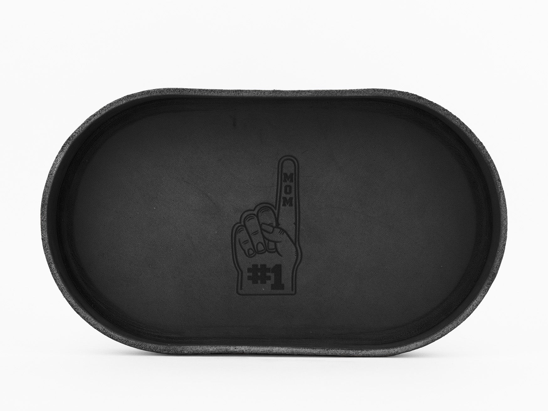 A black oval tray with an engraving of a foam finger showing “#1 MOM” in the center. The design features an upright index finger with the words “MOM” on the finger and “#1” at the base.
