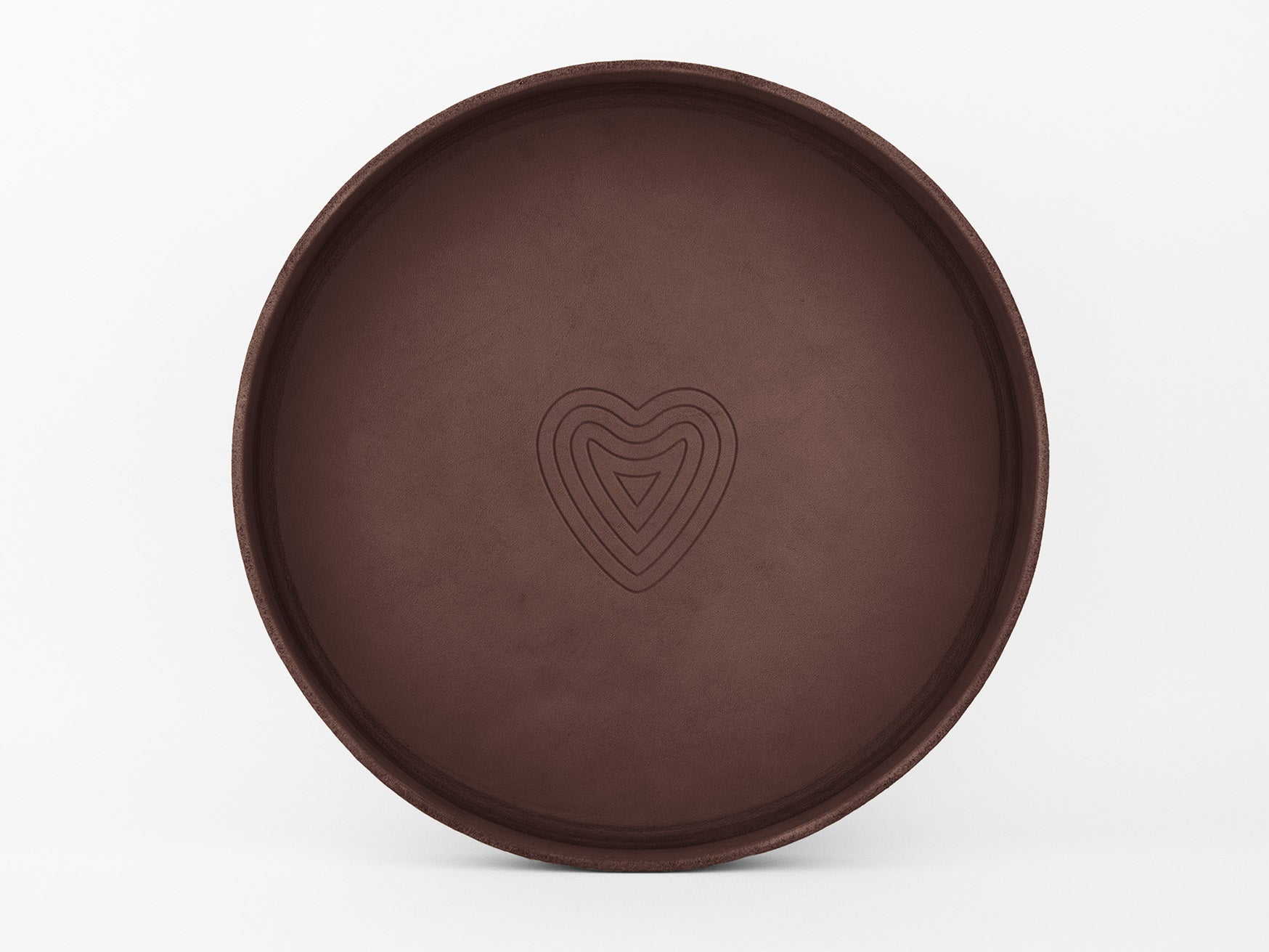A round, brown tray with a simple, engraved heart-shaped pattern in the center, set against a plain white background.