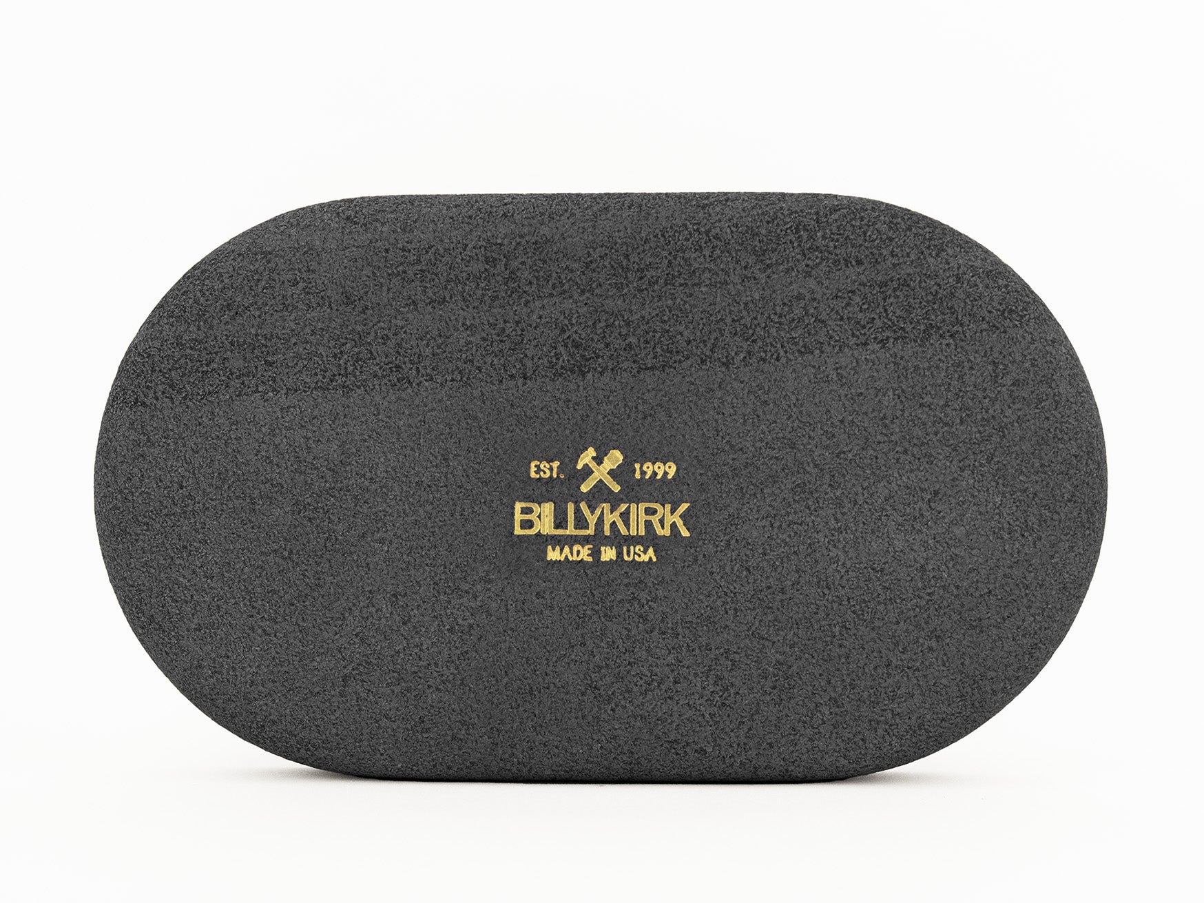 A black oval-shaped object with a textured surface, featuring gold text and crossed hammer graphics that read: Est. 1999 BILLYKIRK MADE IN USA.