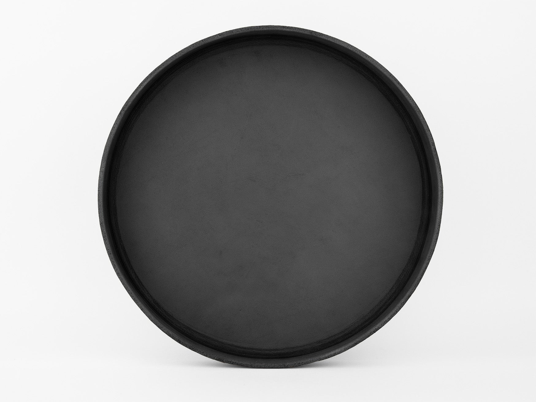 A plain, round, black tray with a raised edge, photographed against a white background.