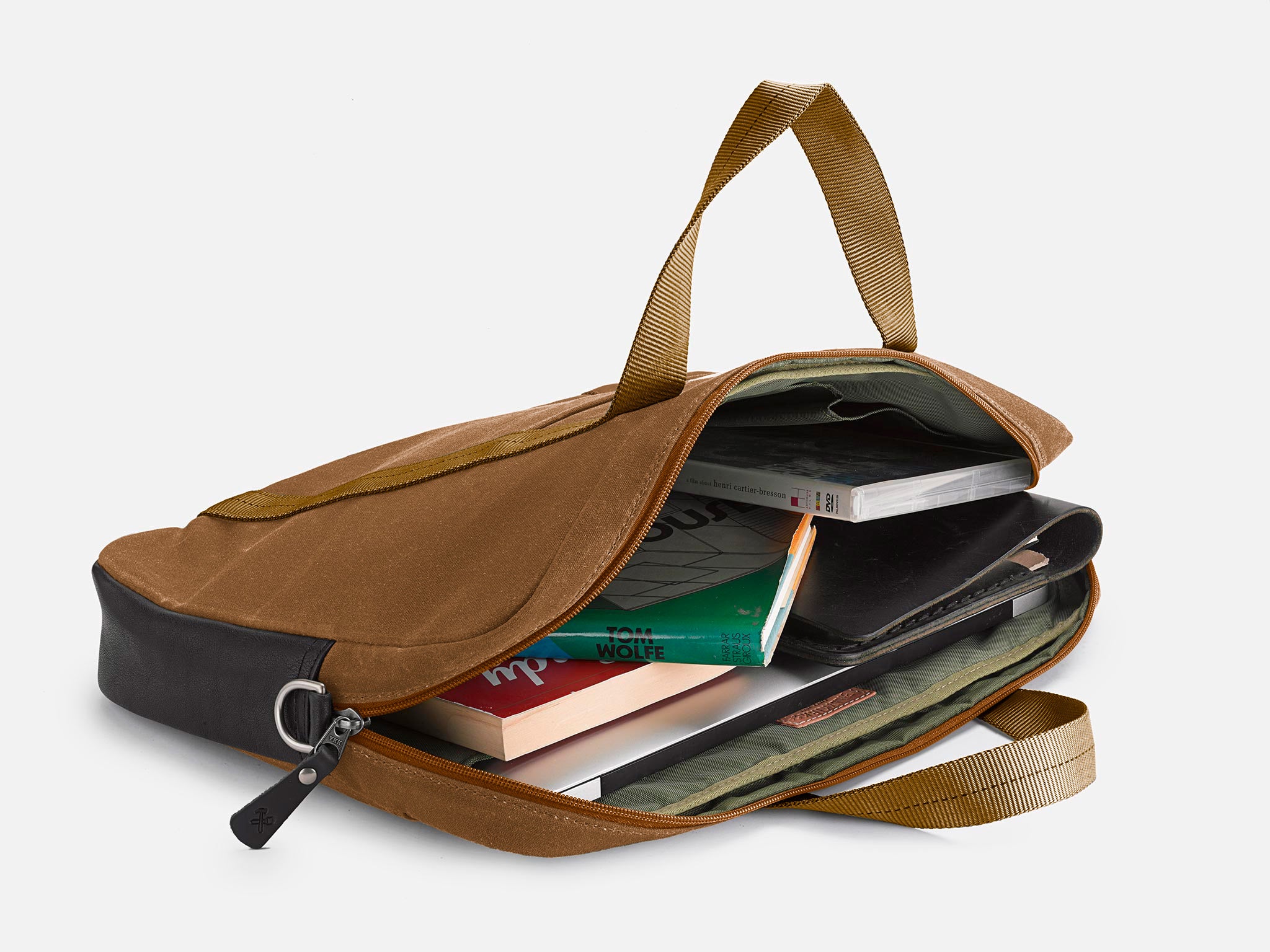 A brown waxed canvas zippered briefcase is open, revealing books, a green zipper pouch, and folders neatly organized inside.