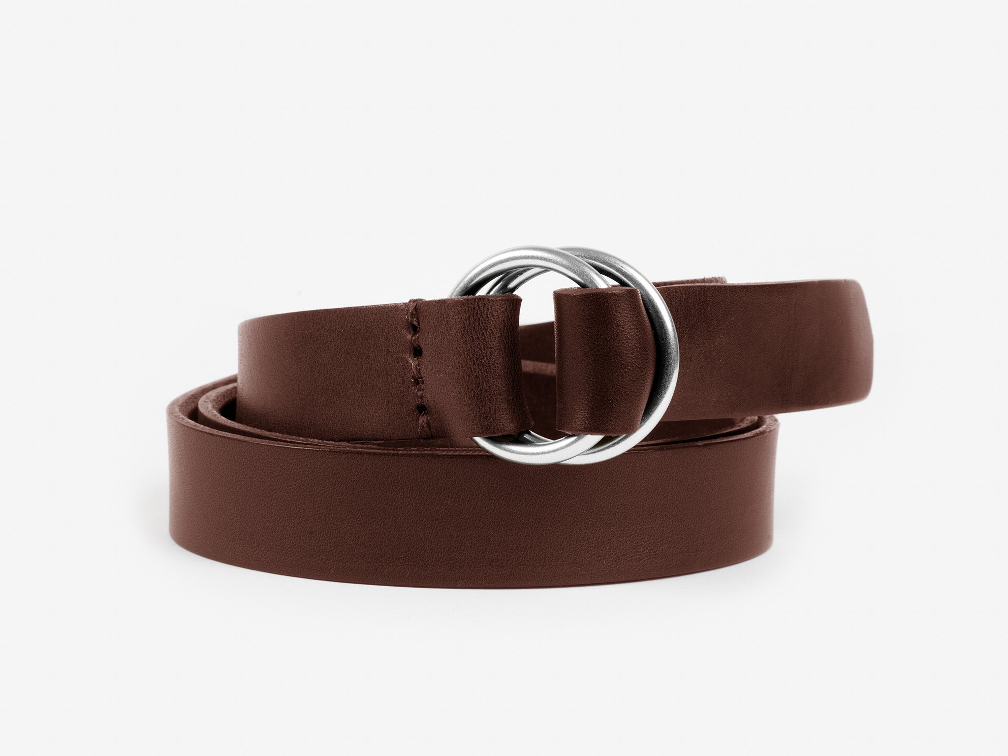 A brown leather belt with a double silver ring buckle, coiled neatly on a white background.