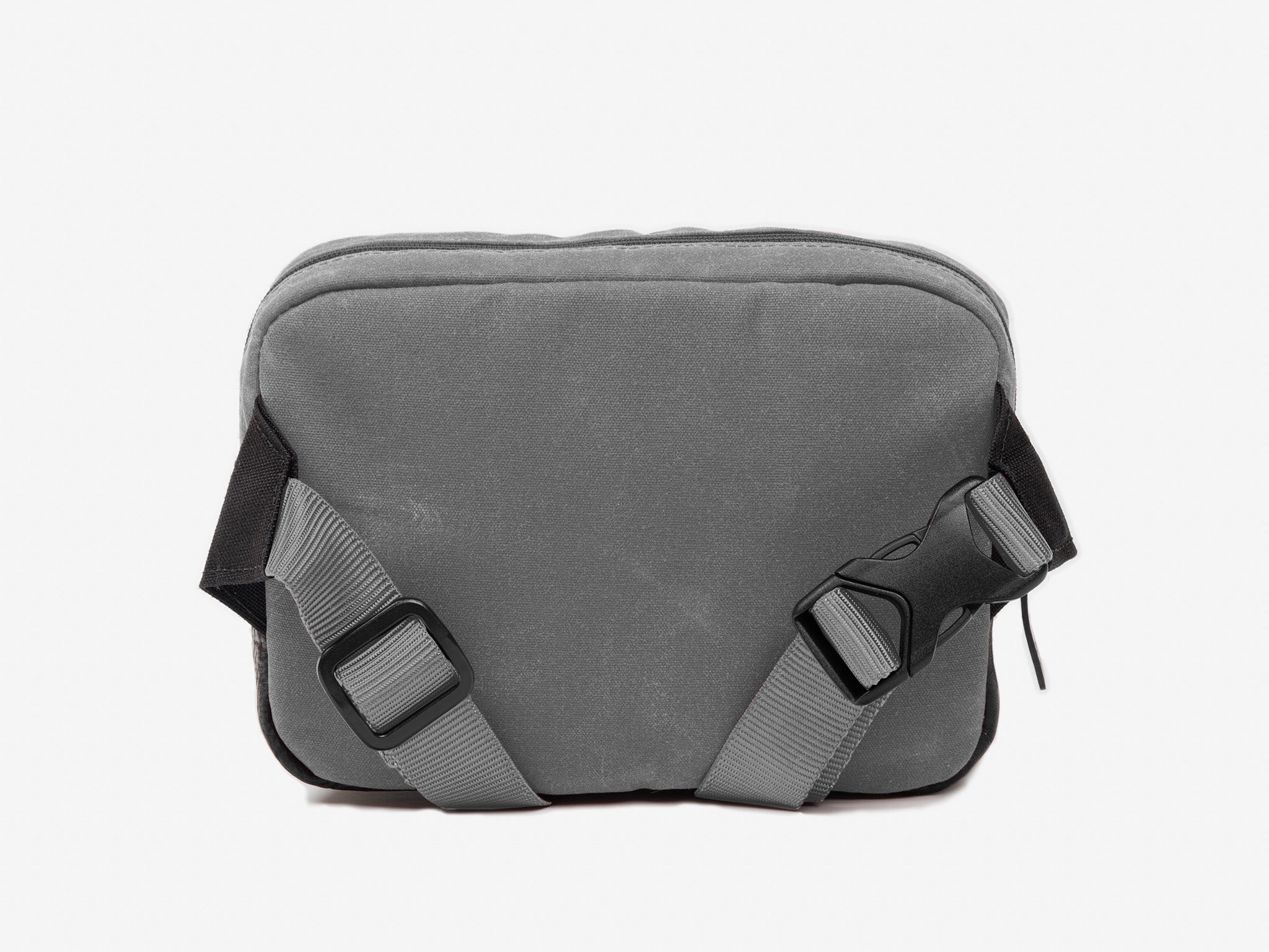 Back view of a small ash waxed canvas crossbody bag with adjustable strap.
