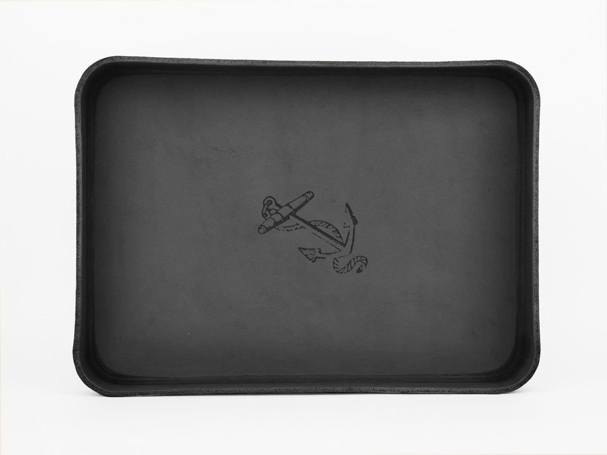 A rectangular black tray with raised edges and an illustration of an anchor and rope in the center on a plain white background.