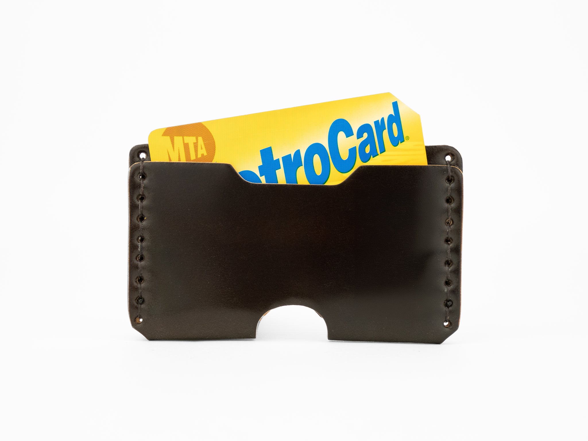 A dark brown cordovan leather card holder with a yellow and blue MTA MetroCard partially visible inside.