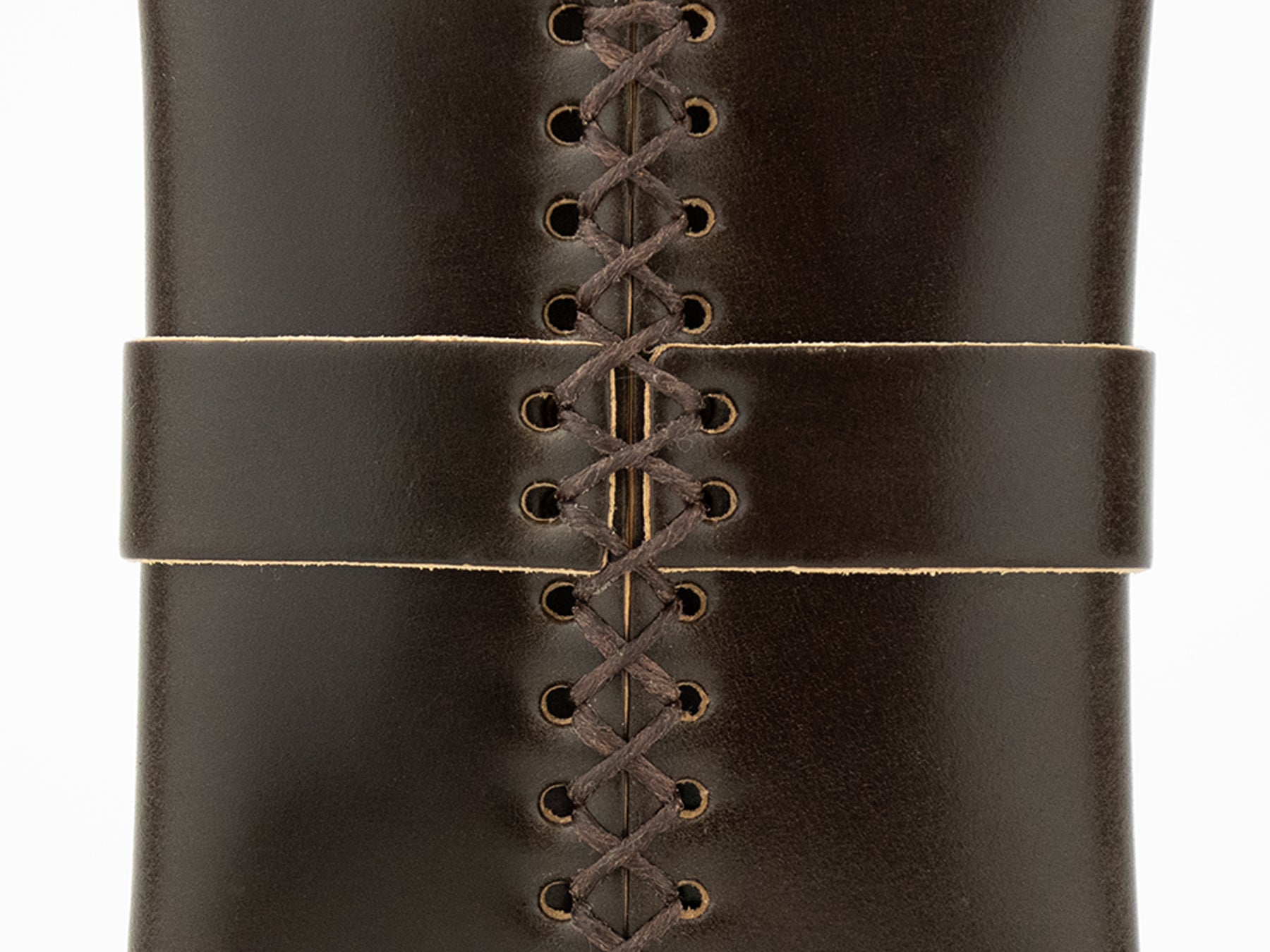 A closeup of a dark brown cordovan leather wallet with visible stitching and crisscross lacing down the center, as well as a horizontal leather strip across the front. The pouch has a smooth, shiny finish.