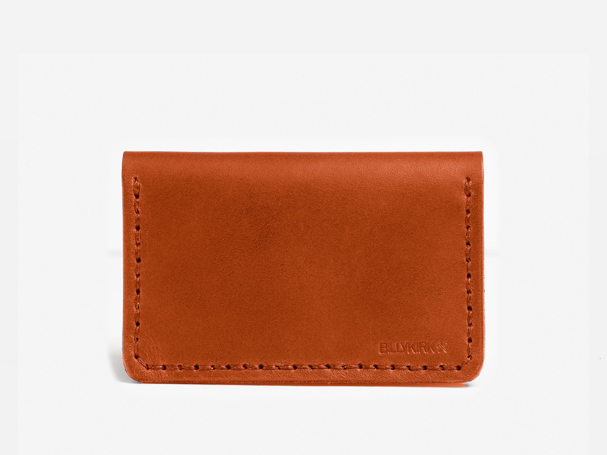 A minimalist brown leather card holder with visible stitching around the edges and the brand name BLYKRK subtly embossed in the bottom right corner.