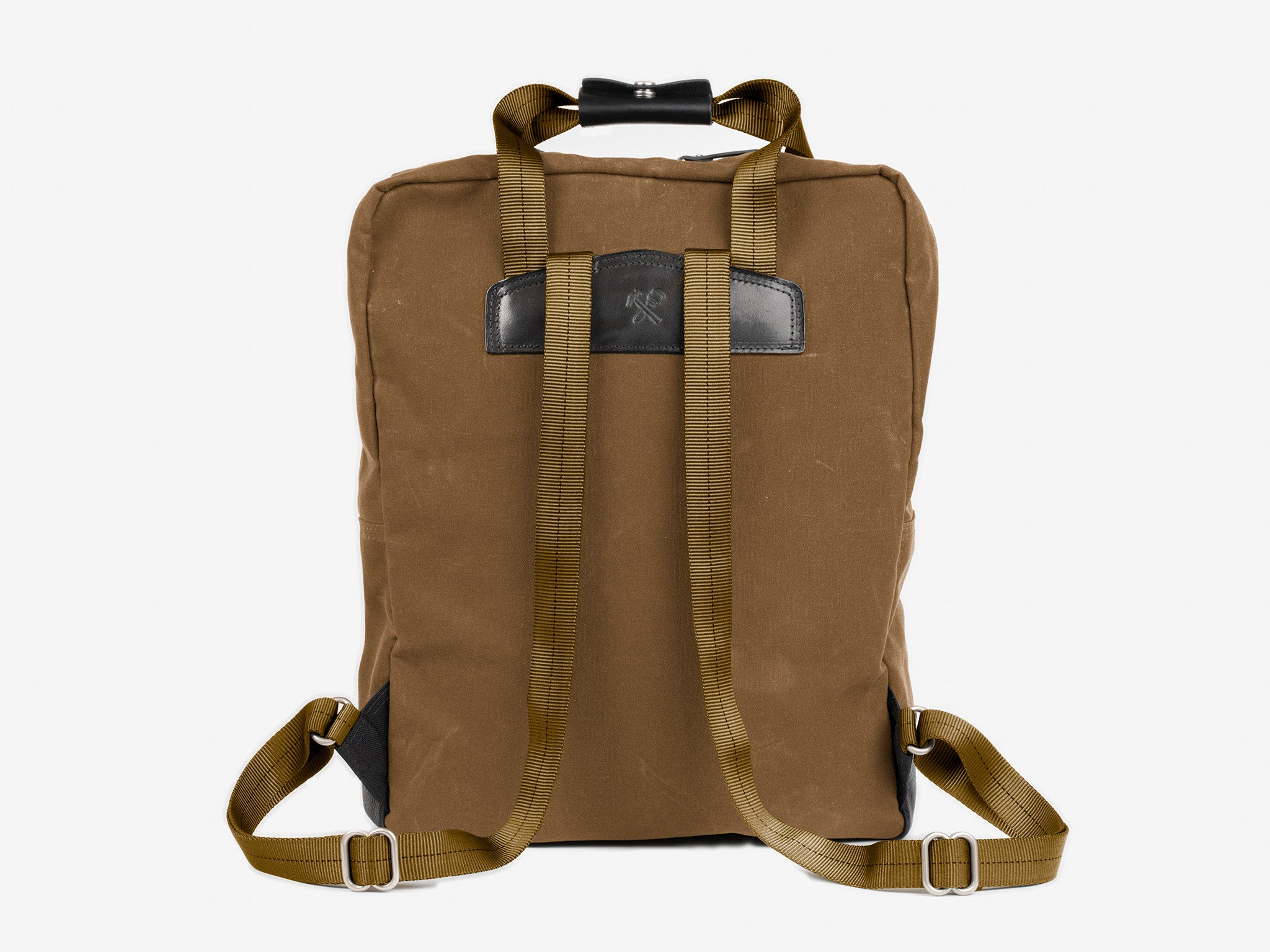 A brush brown waxed canvas backpack shown from the back, featuring adjustable shoulder straps, a top handle, and a rectangular black leather patch near the top center. The background is plain white.