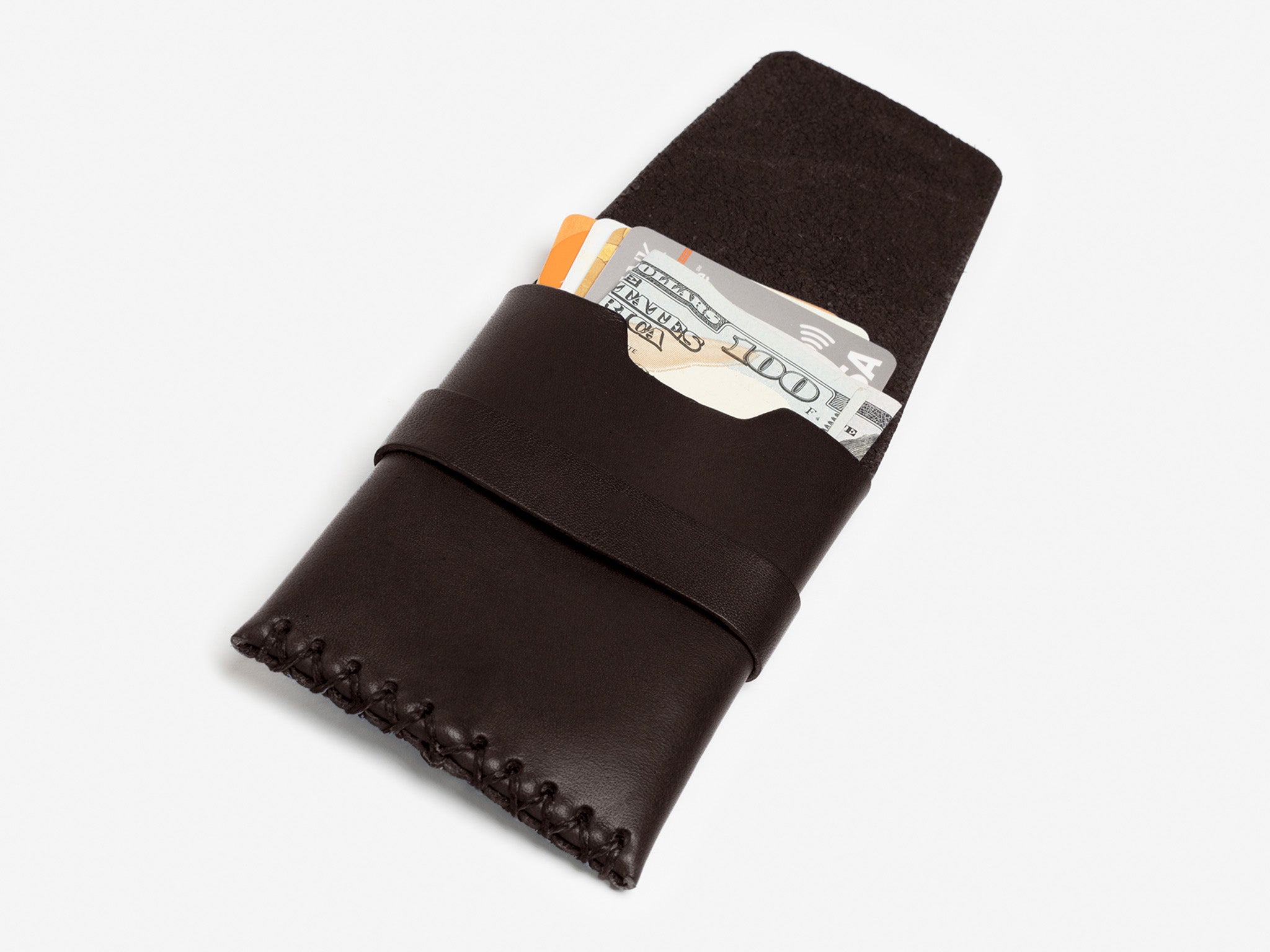 A dark brown leather wallet with visible stitching holds a folded $100 bill, and credit cards, all partially sticking out of the wallet on a white background.
