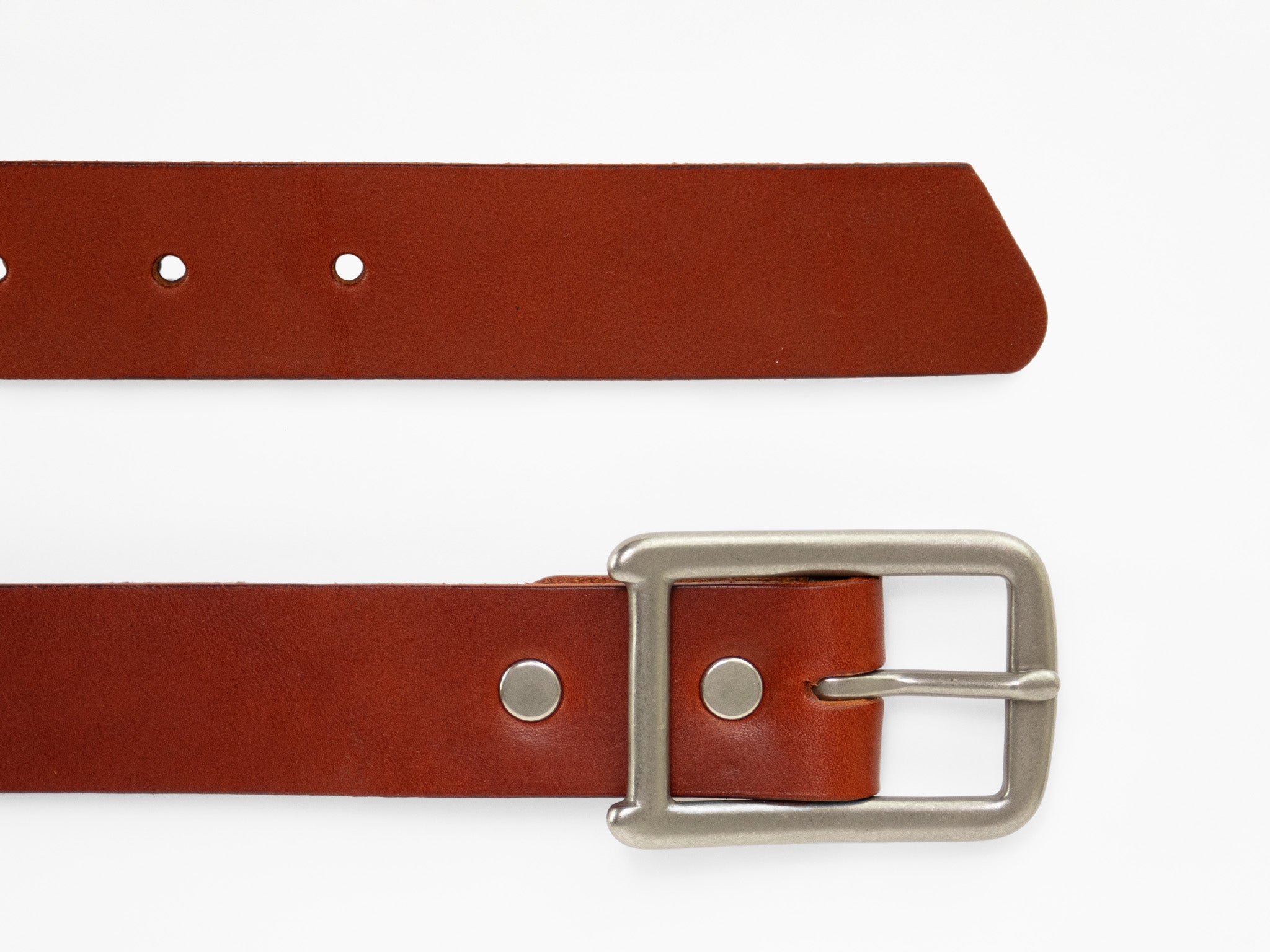 A brown leather belt with a silver buckle is laid flat on a white background. The belt has metal rivets and holes for fastening.