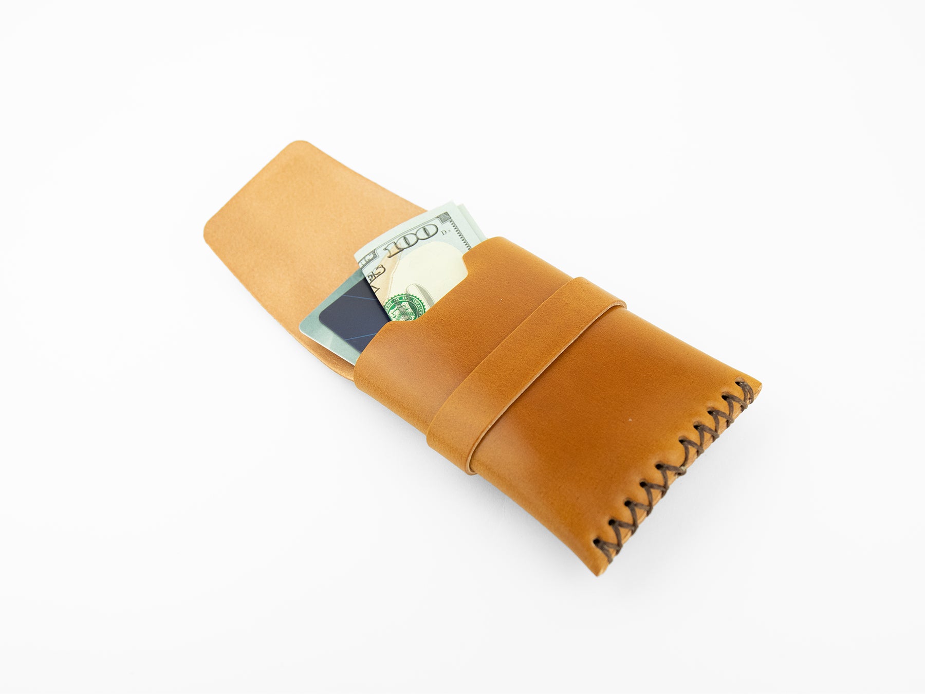 A tan leather wallet with black stitching, partially open, holding a folded US $100 bill and a credit card, displayed on a white background.