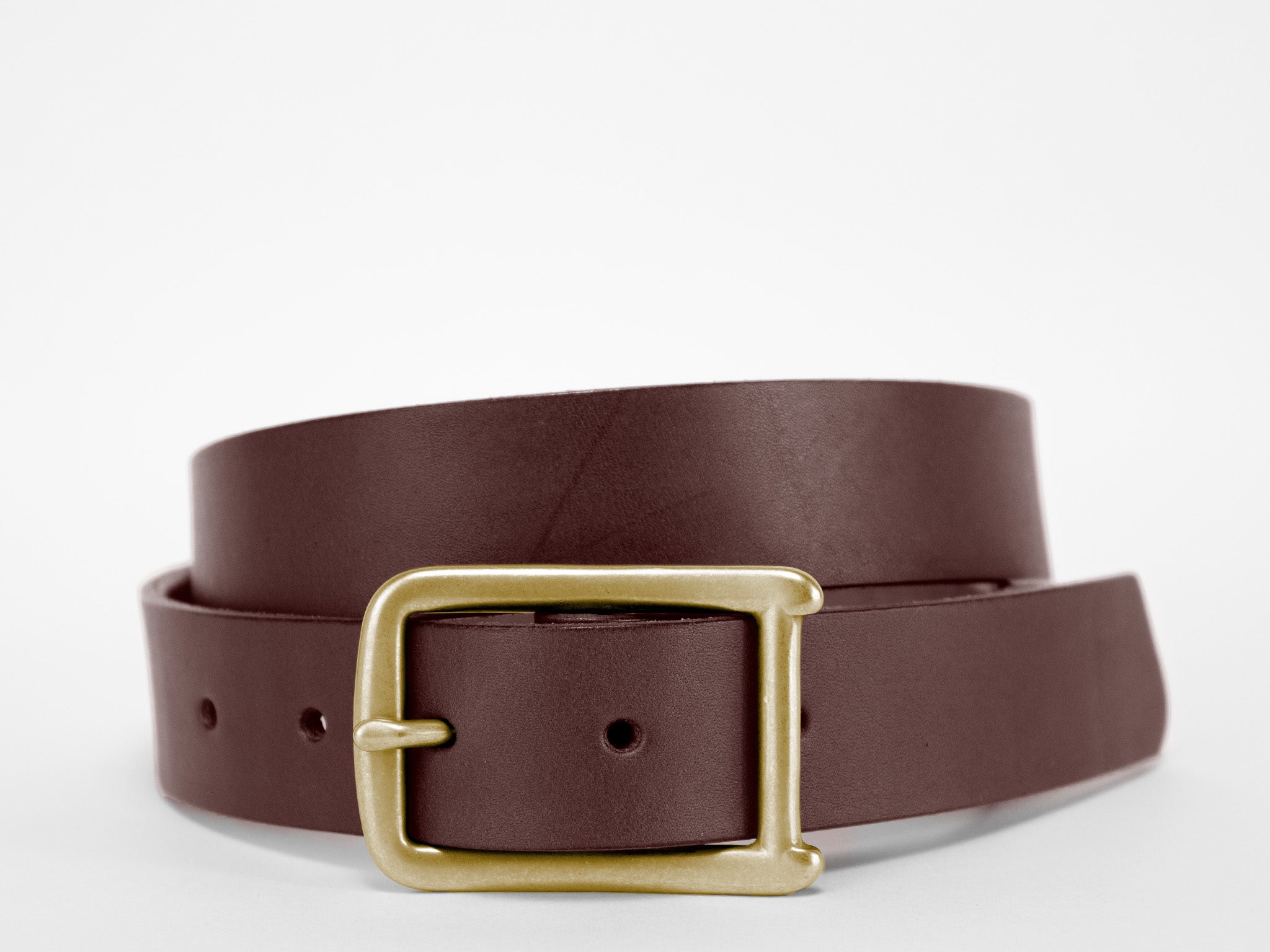 A brown leather belt with a gold rectangular buckle is coiled neatly against a plain white background.