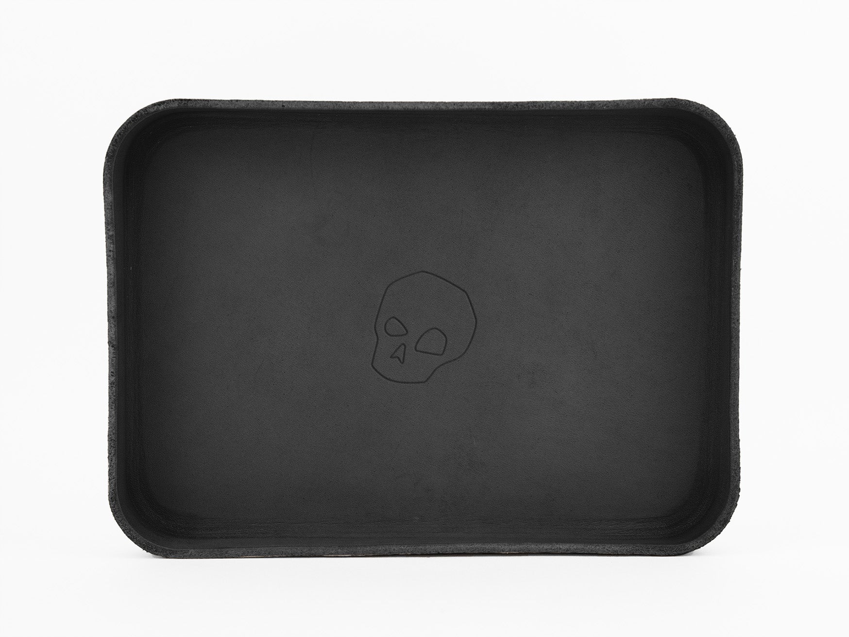 A rectangular black tray with rounded corners features a simple outline of a skull in the center. The background is white, emphasizing the trays dark color and minimalist design.