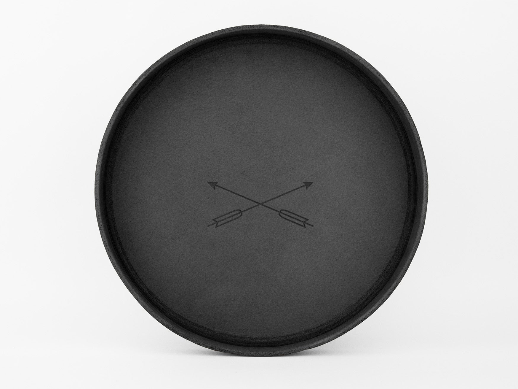 A round, black tray with a simple design of two crossed arrows in the center, set against a plain white background.