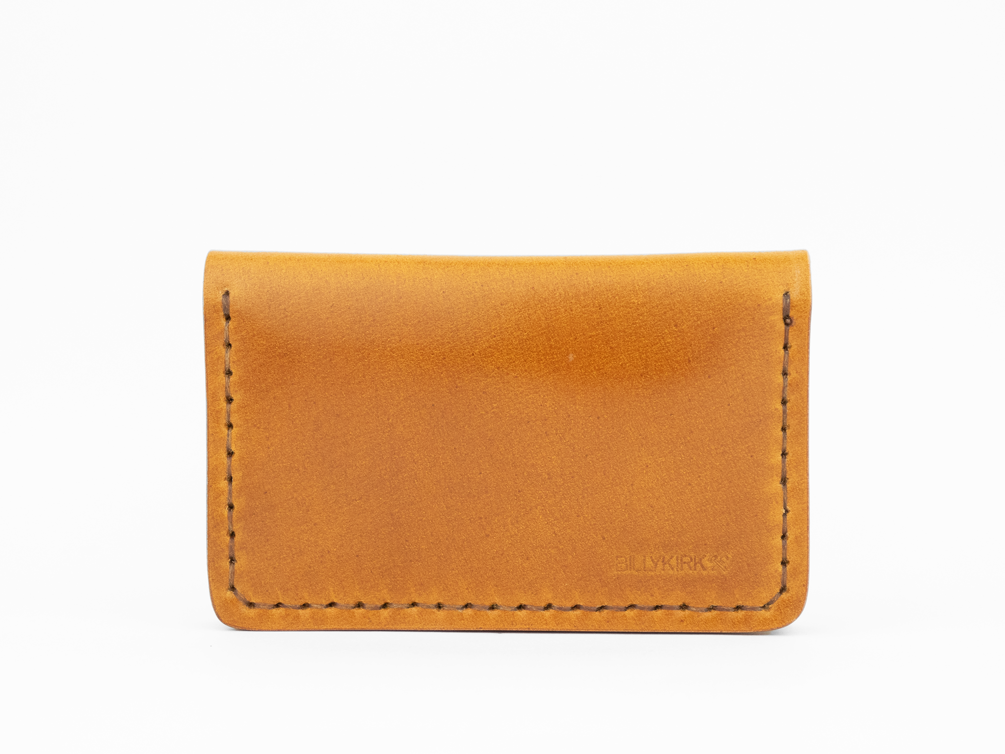 A minimalist, tan cordovan leather cardholder wallet with visible stitching around the edges and a subtle embossed BILLYKIRK logo in the lower right corner, set against a white background.
