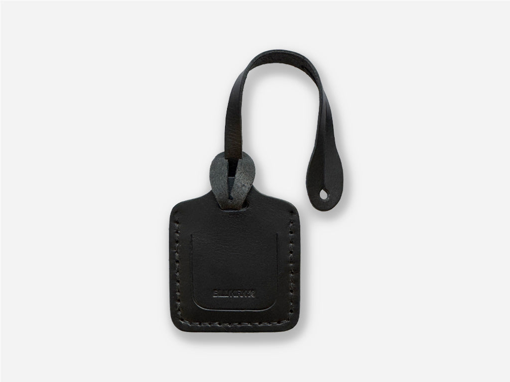 Black leather luggage tag with a strap on a white background