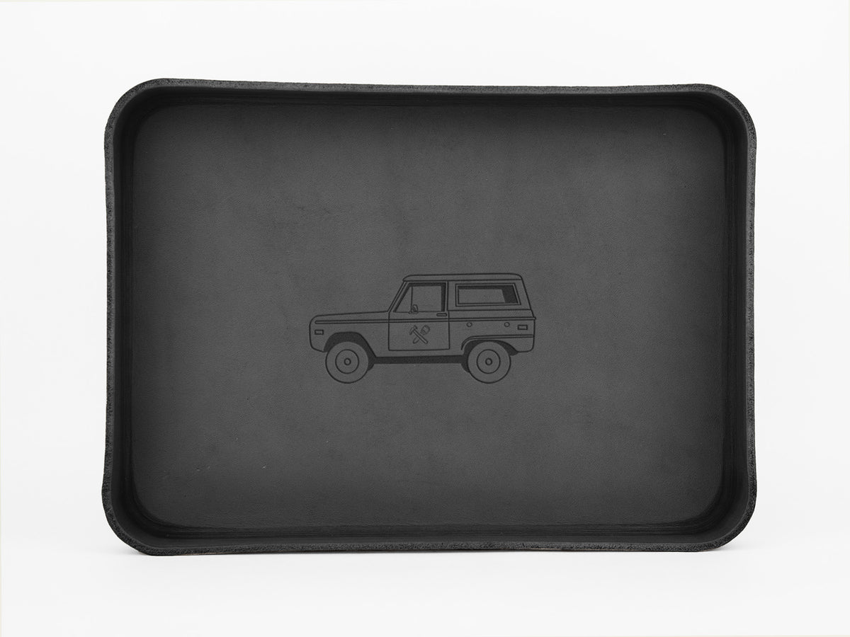 A black rectangular tray with raised edges featuring a simple outline drawing of an SUV-style vehicle in the center. The background is plain white.