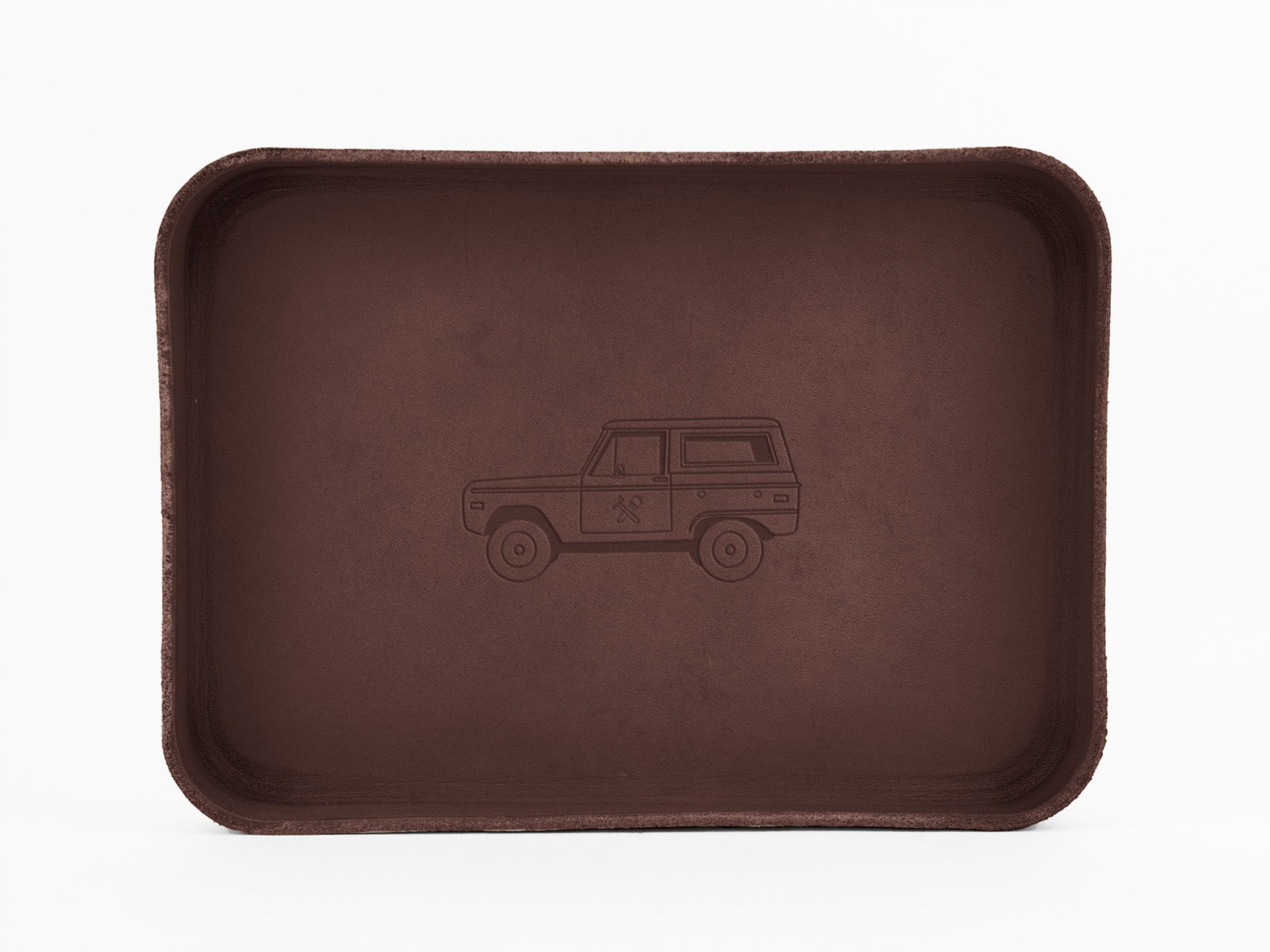 A rectangular brown tray with rounded corners features an outline drawing of a vintage SUV engraved in the center. The background is plain white.