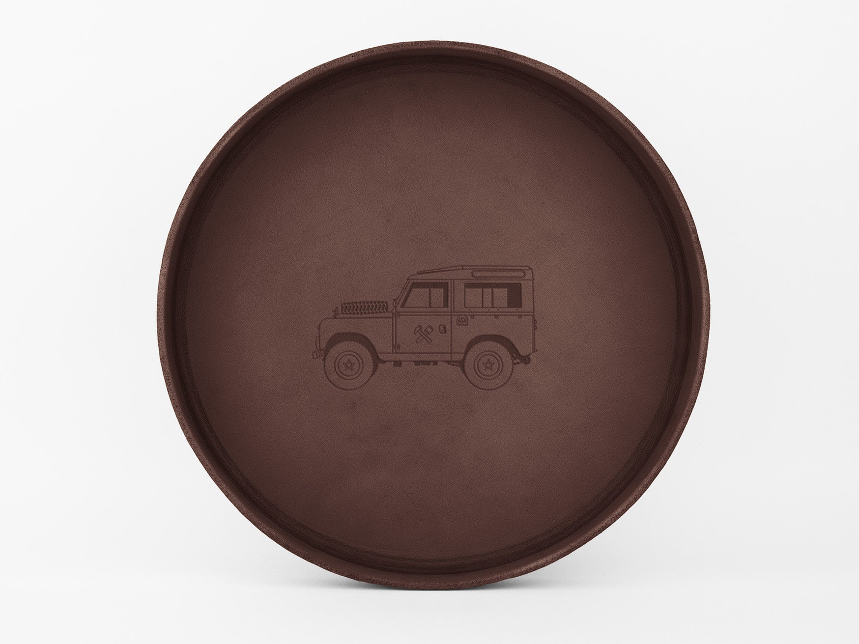 A round, brown tray with a simple engraved illustration of a classic off-road vehicle, viewed from the side, centered inside the tray.