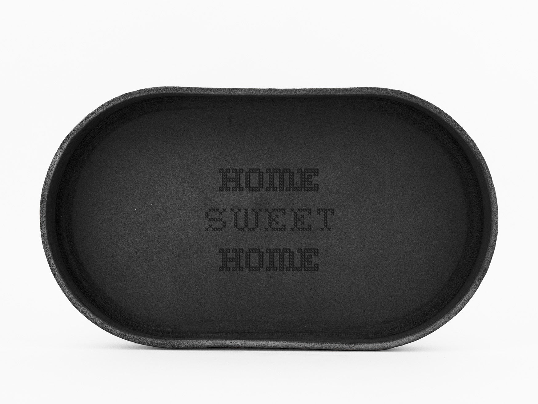 A black, oval-shaped doormat with the words HOME SWEET HOME written in pixelated uppercase letters in the center. The background is plain white.