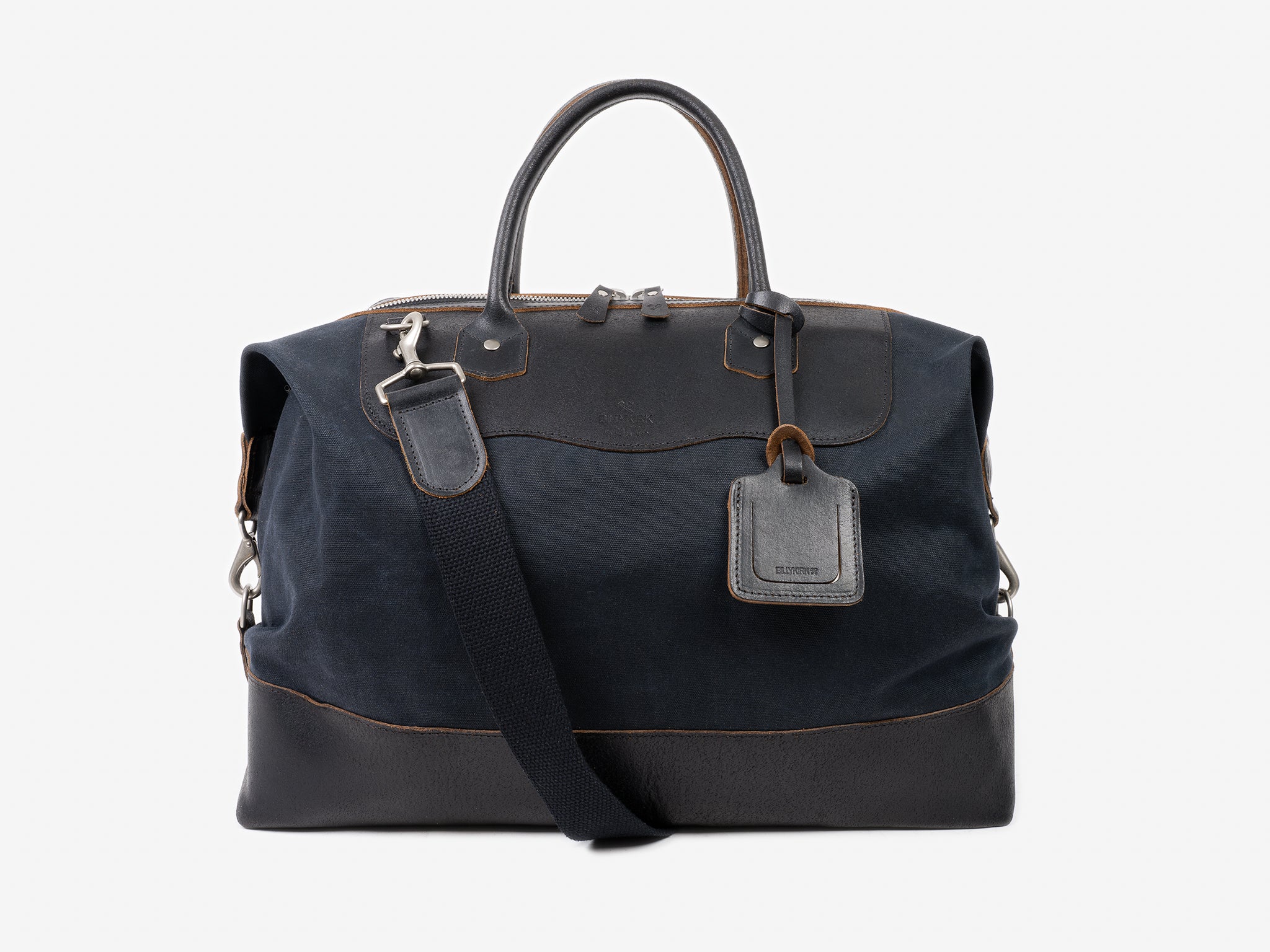 A black and dark navy leather duffel bag with a top zipper, two handles, a detachable shoulder strap, and a leather luggage tag, displayed against a plain light gray background.