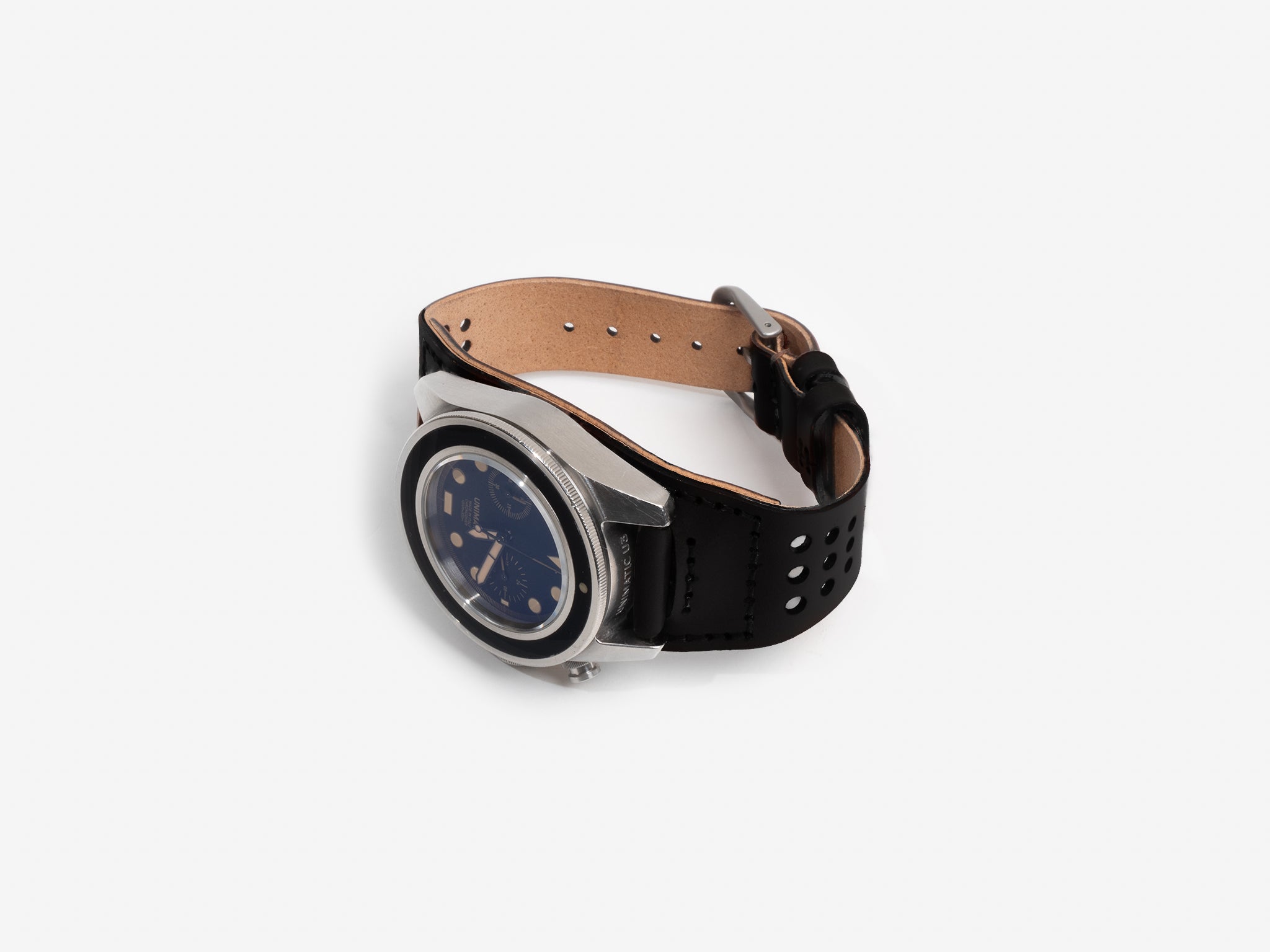 A fastened black cordovan leather watch strap, silver buckle, and a round black dial featuring multiple subdials and gold accents, displayed flat on a white background.