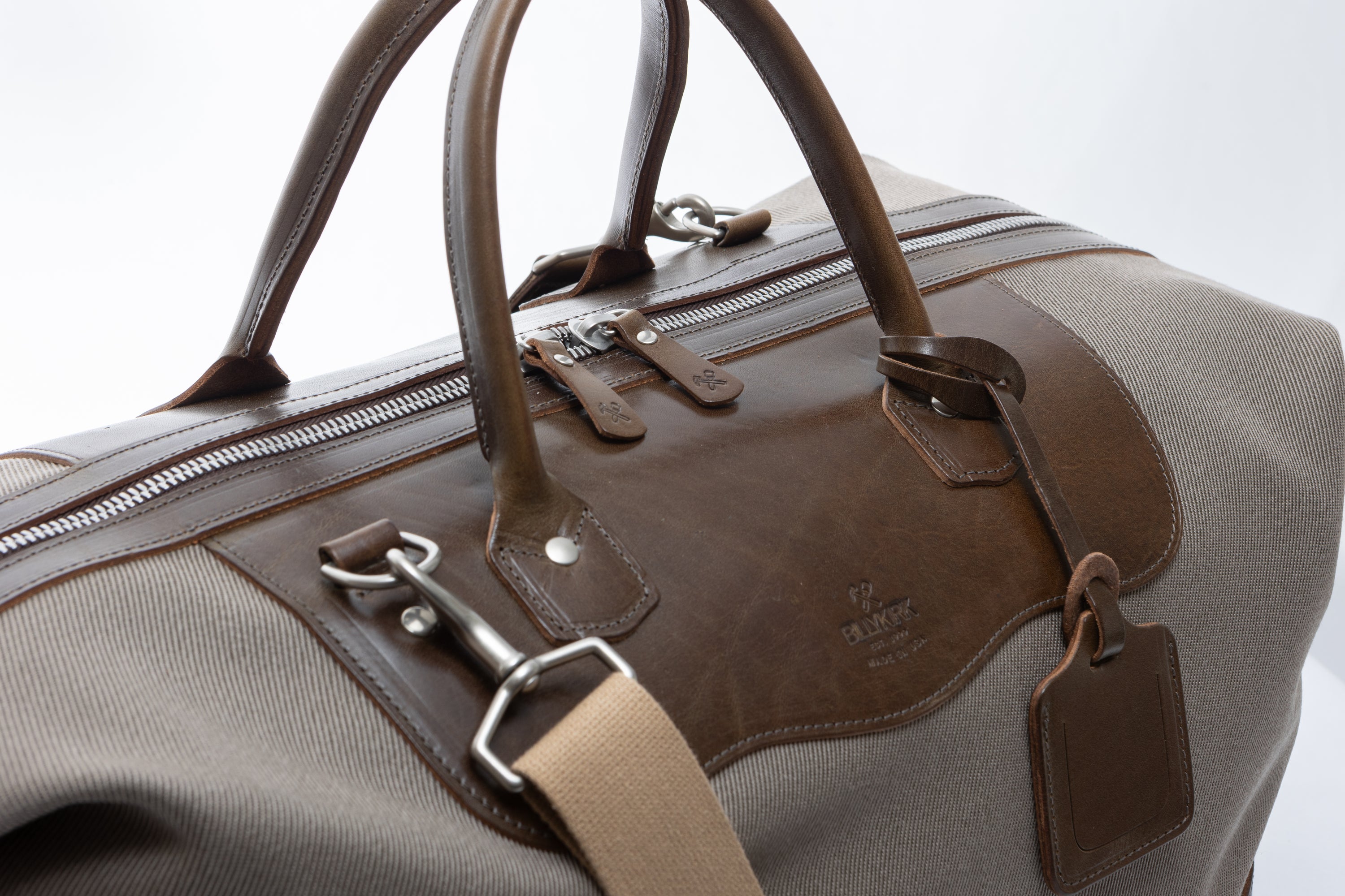 olive leather and beige fabric bag with a strap on a white background