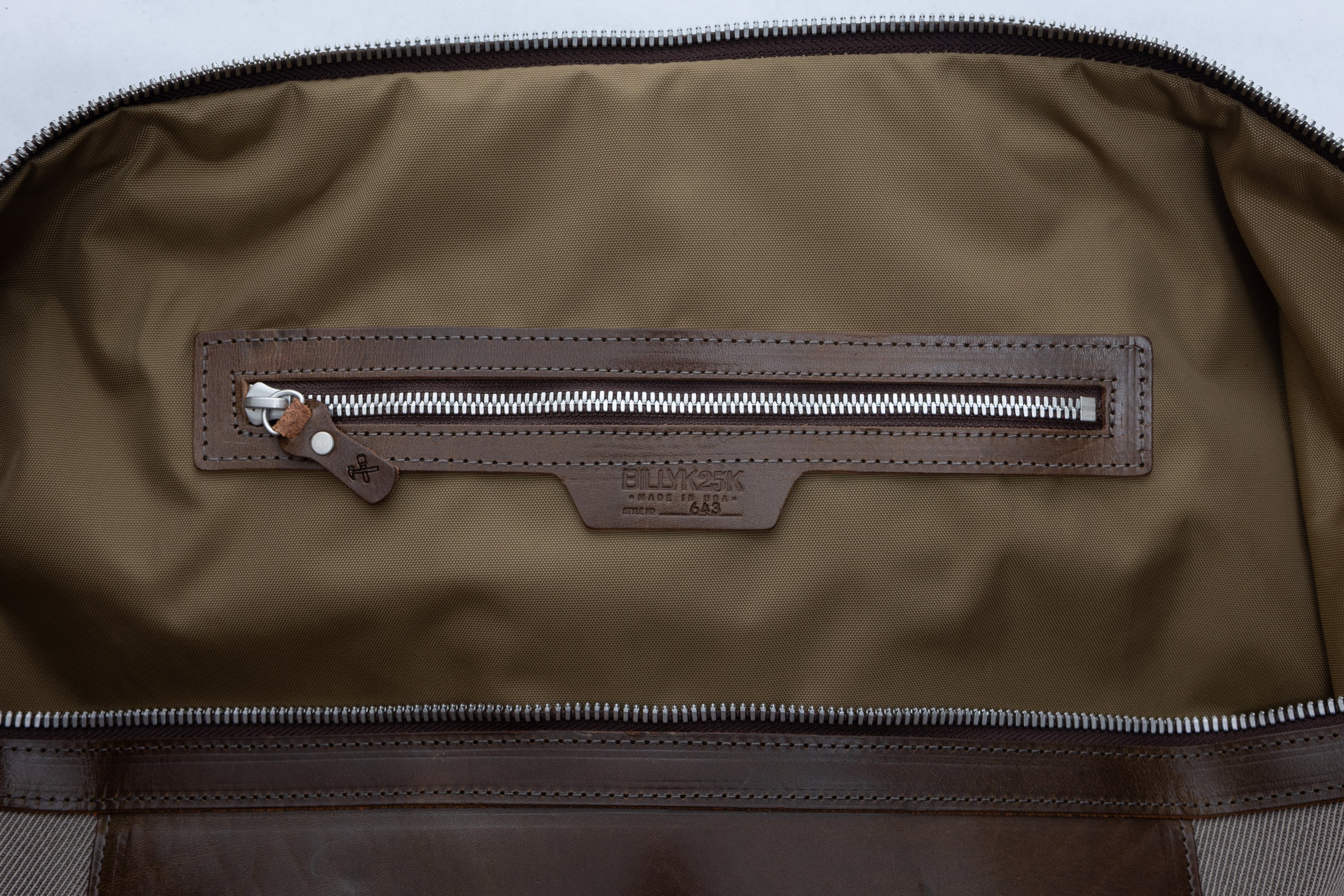 olive nylon interior with a zipper on a light gray background