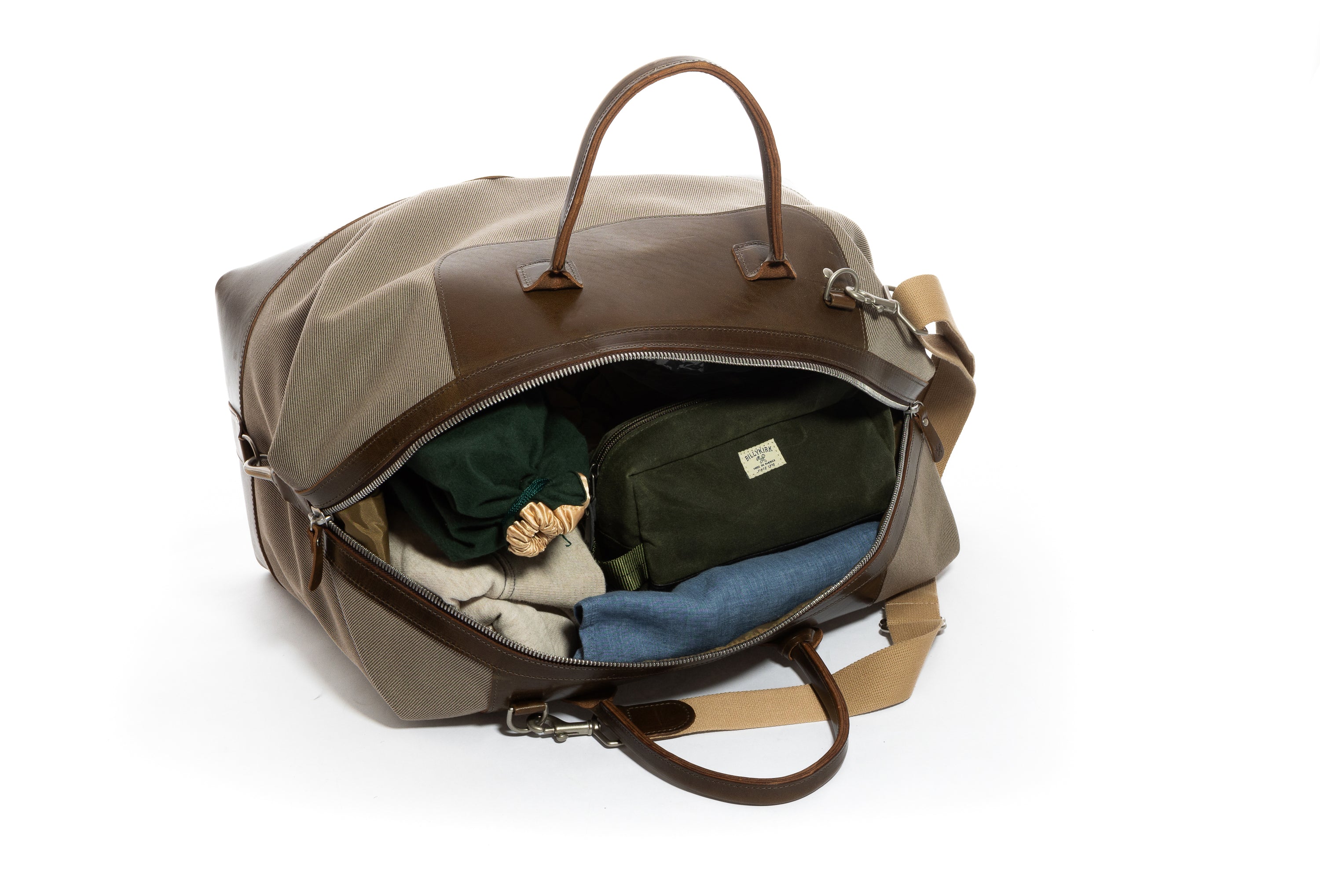 Open travel bag with clothes and a toiletry bag on a white background