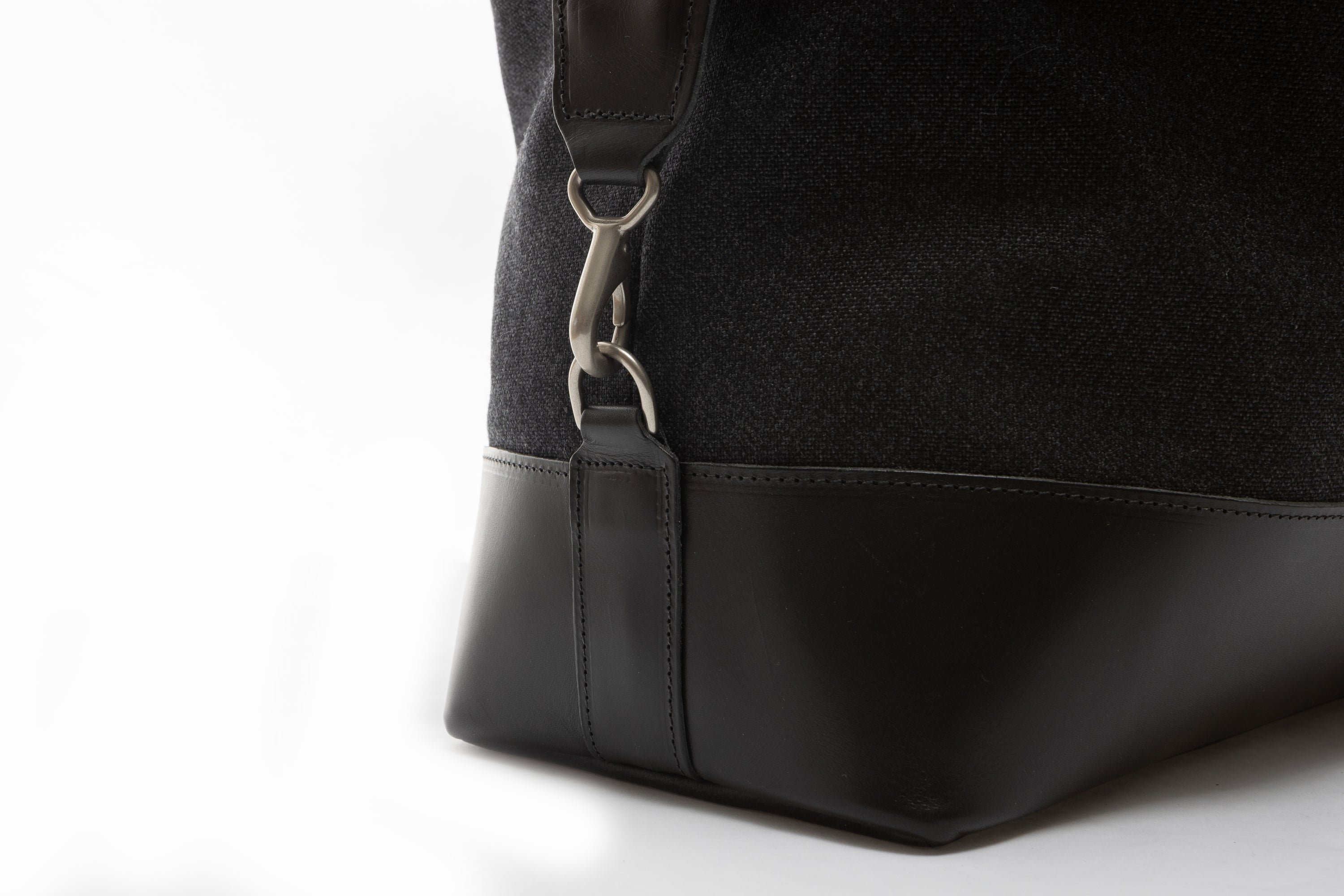 Close-up of a black bag with a silver hardware on a white background