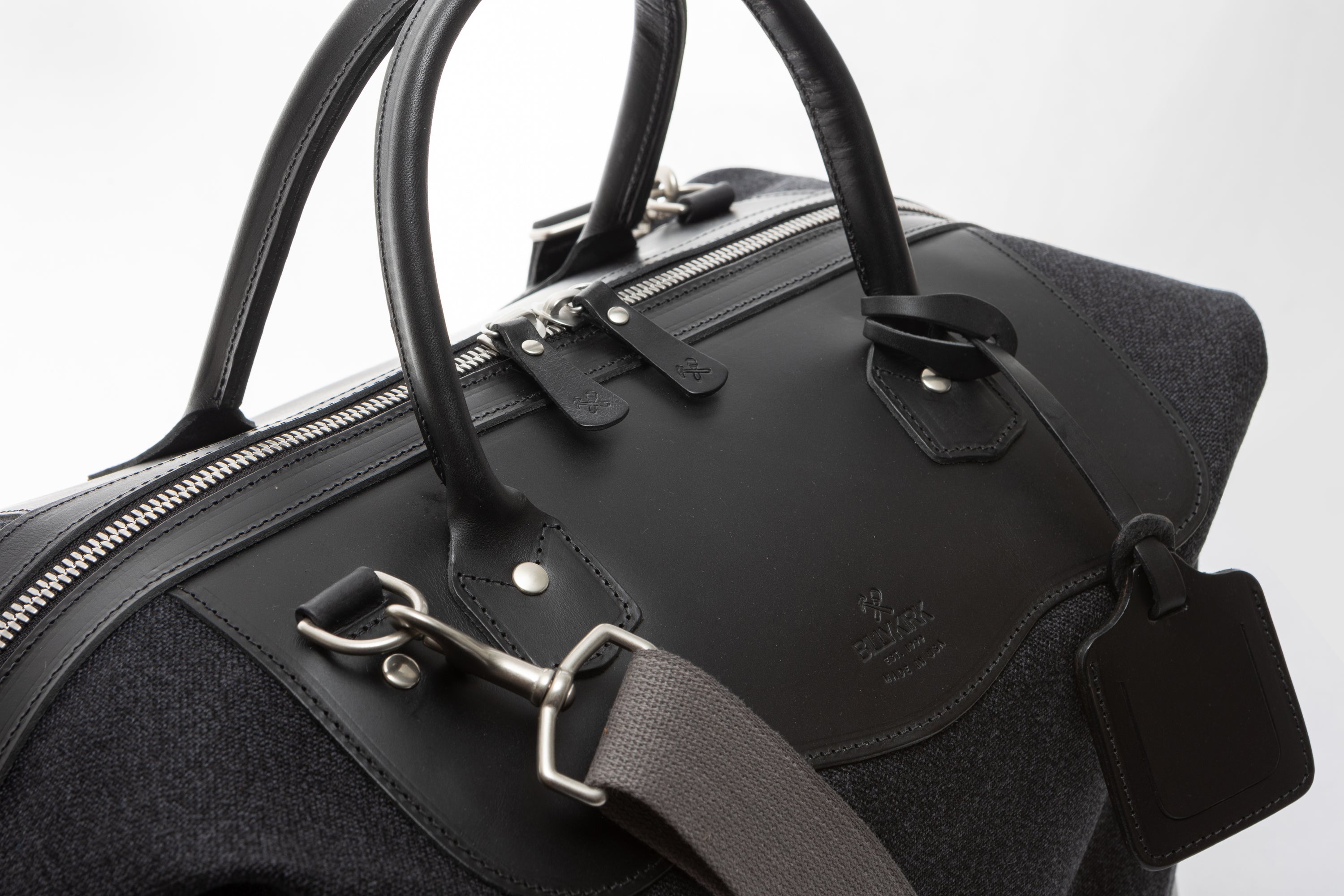 Black leather handbag with silver hardware on a light gray background