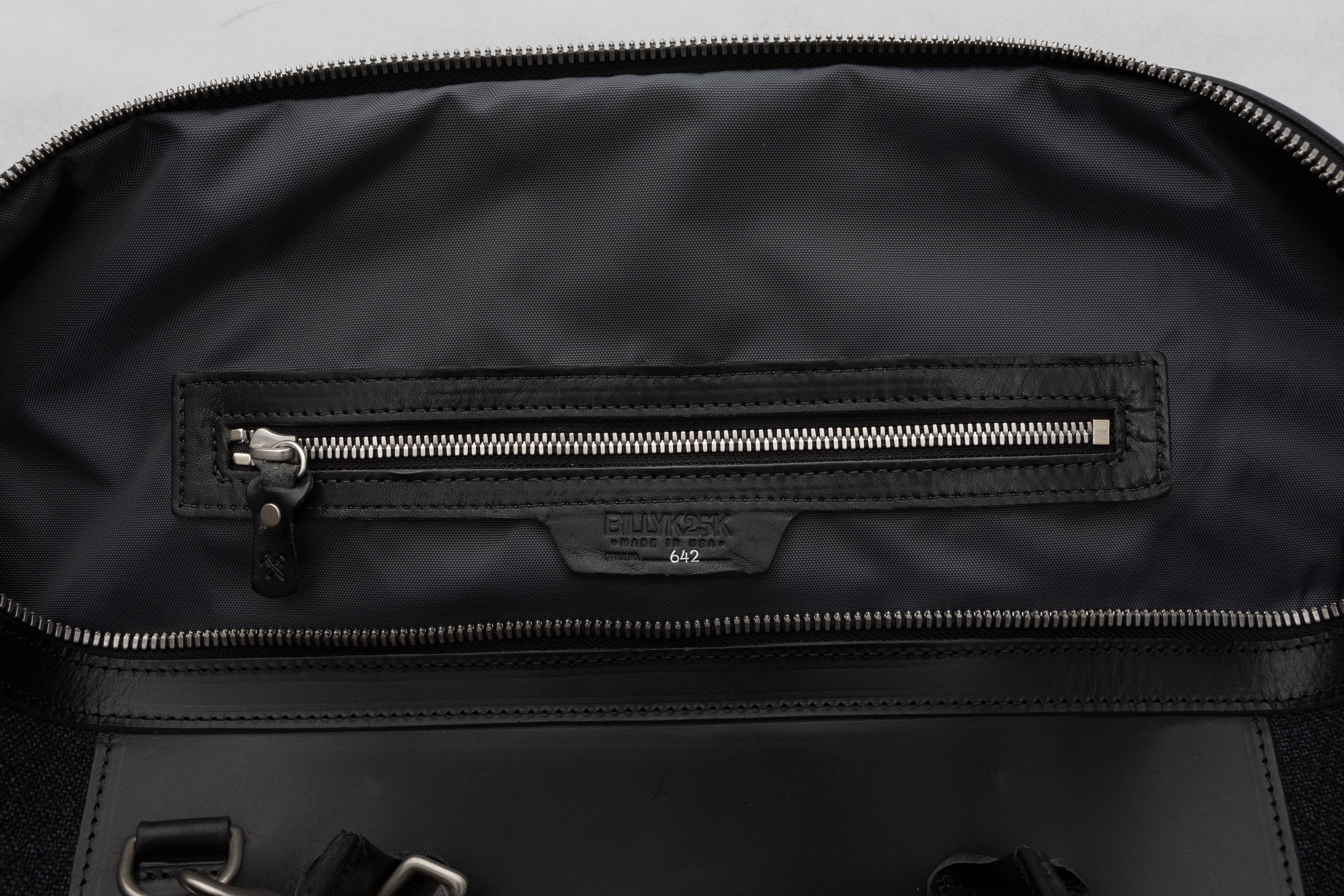 Interior of black carryall with a zipper on a gray background