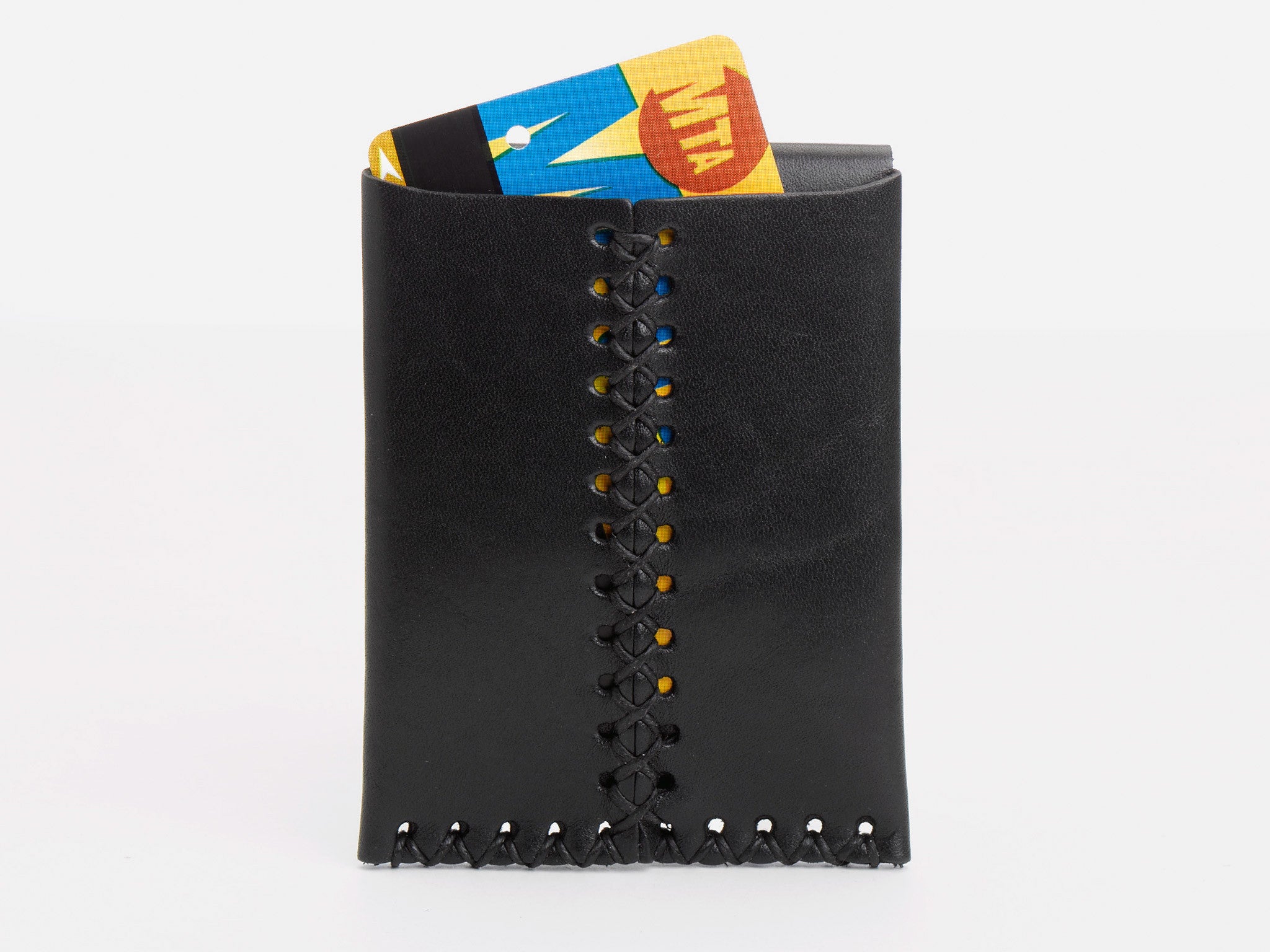 A black leather wallet with visible stitching holds an MTA MetroCard partially sticking out against a plain white background.