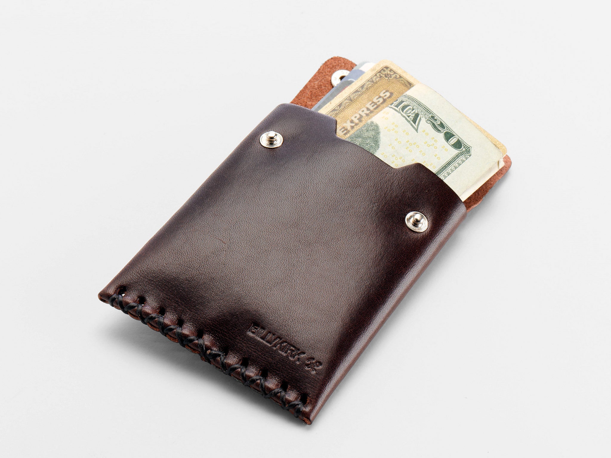 A dark brown leather wallet with snap buttons, partially open to reveal folded U.S. dollar bills and a credit card against a plain white background.