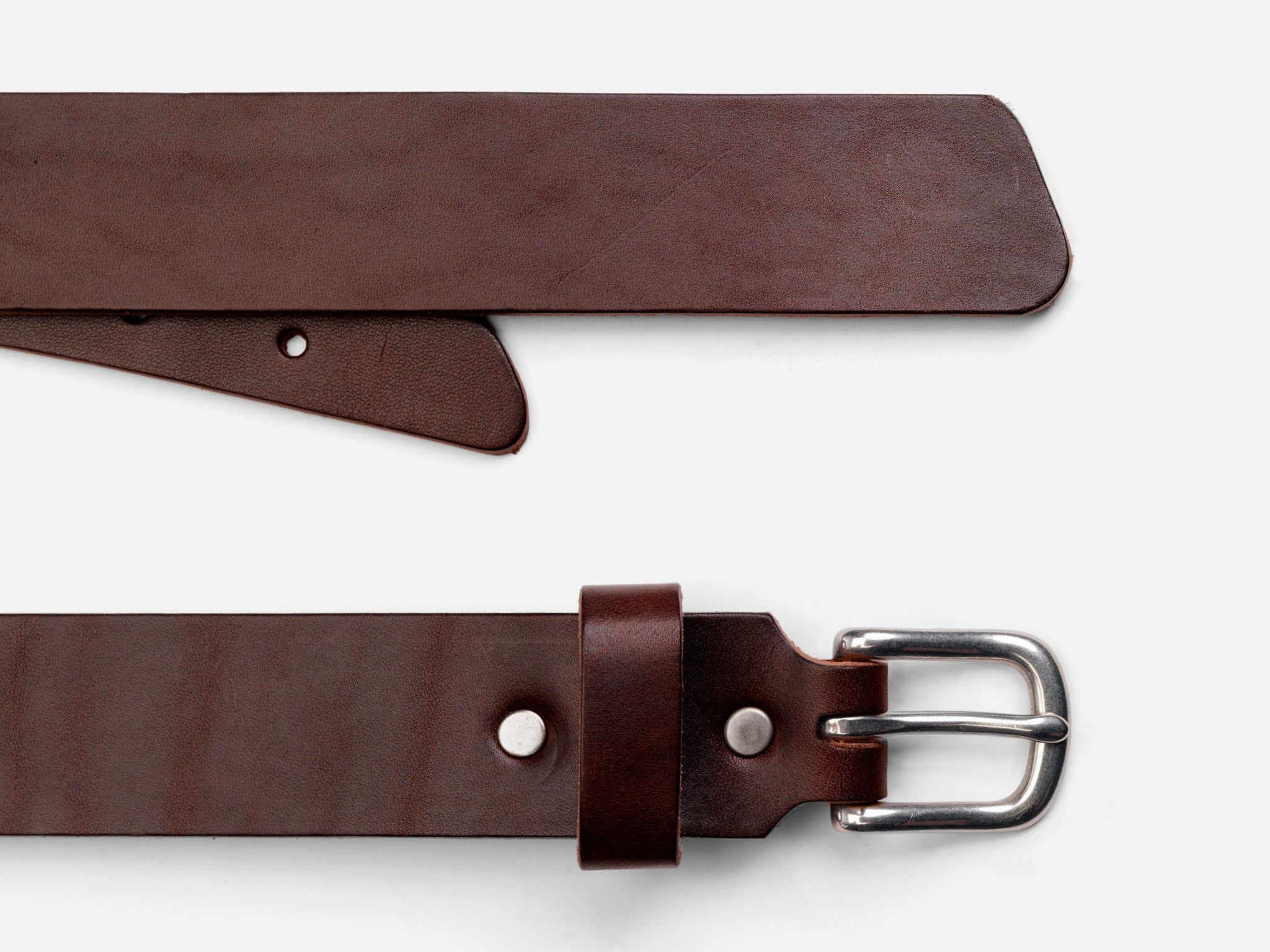 A brown leather belt with a silver buckle is shown laid flat on a white background. The belt is partially unbuckled, displaying both the buckle end and the pointed end with holes.