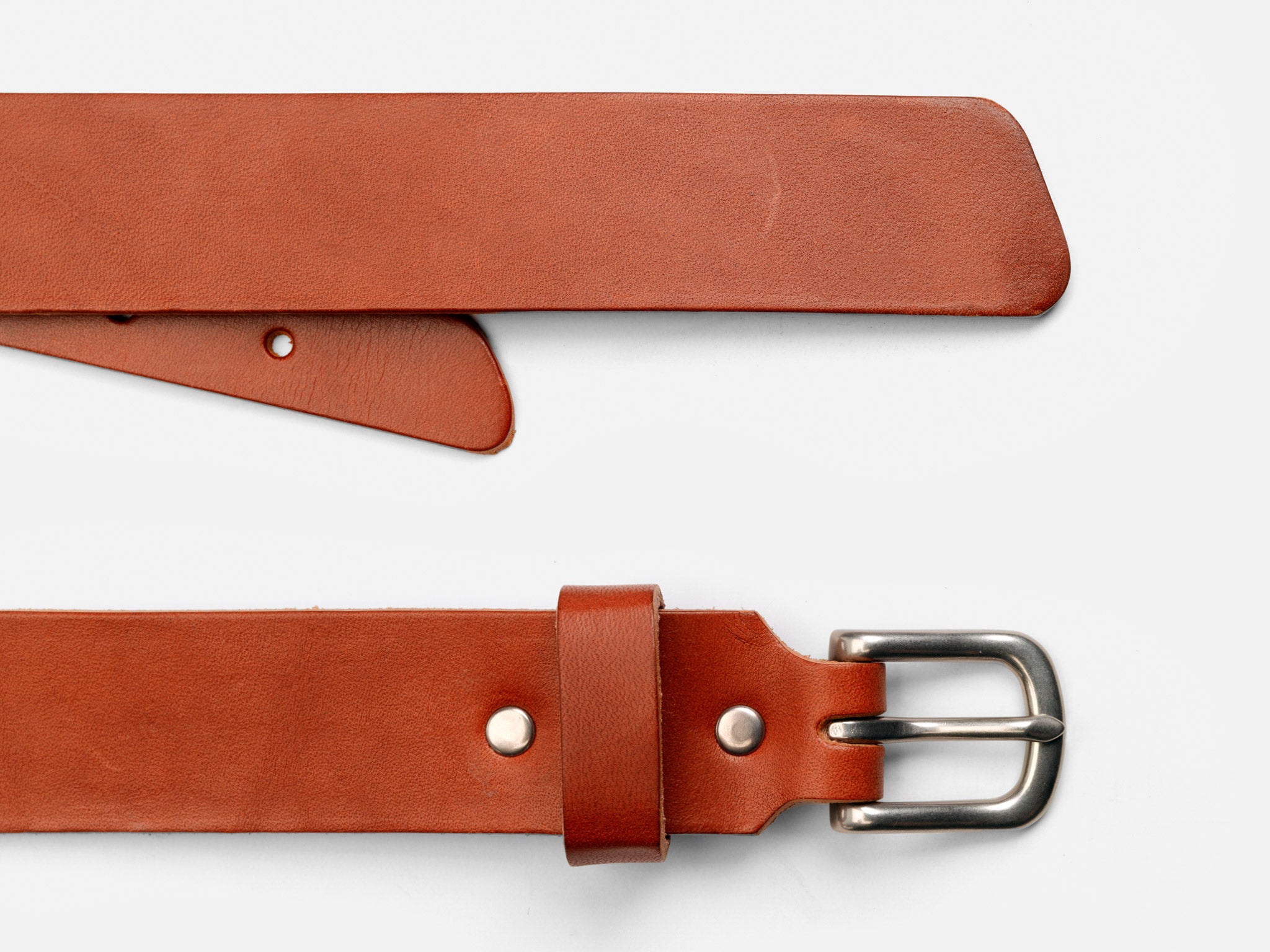 A brown leather belt with a silver buckle and metal rivets, laid flat on a white background. The pointed end and the buckle end of the belt are both visible.