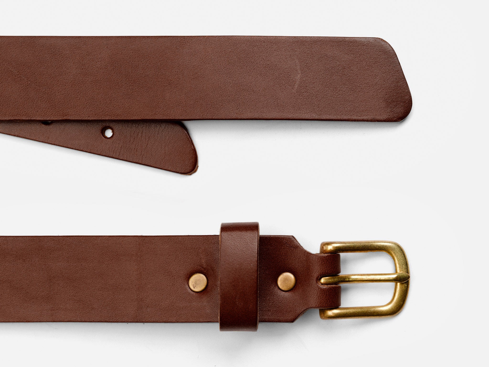 A brown leather belt with a gold buckle is laid flat on a white surface, showing both the buckle end and the pointed tip of the belt.