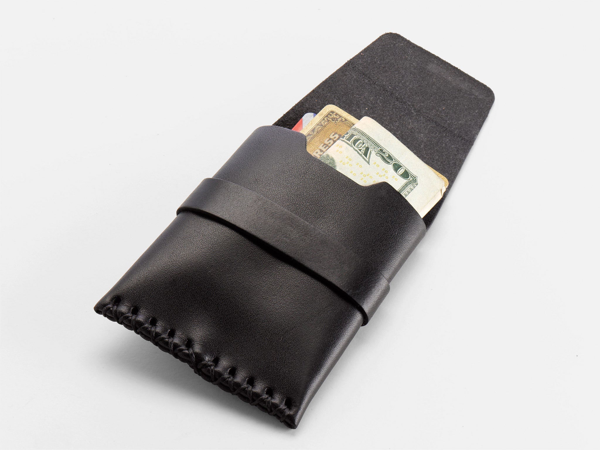 A black leather wallet with visible stitching holds a folded $20 bill, an American Express card, and another credit card, all partially sticking out of the wallet on a white background.