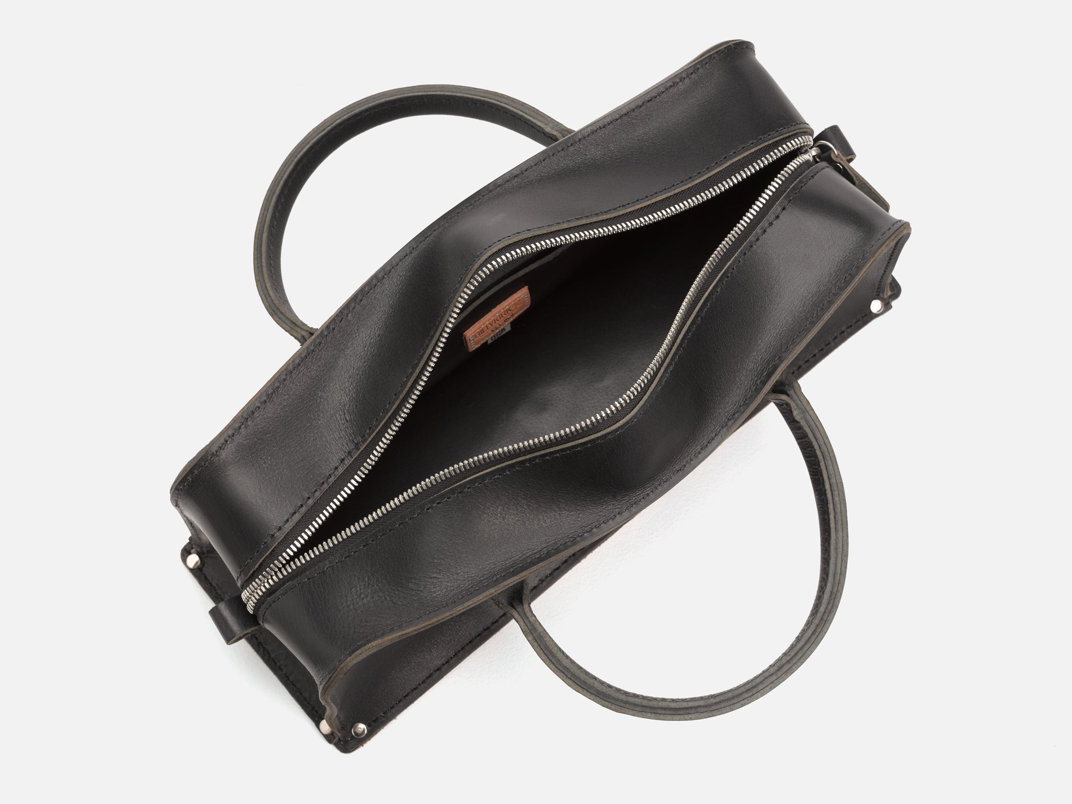 A top view of a black leather tool bag with rivet reinforced corners with zipper open showing the inside of the bag set in a white background
