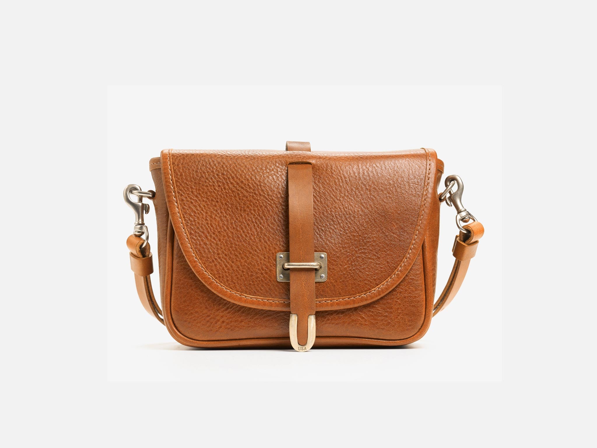 A small brown leather crossbody bag with a curved flap, metal buckle closure, and adjustable strap, displayed on a plain white background.