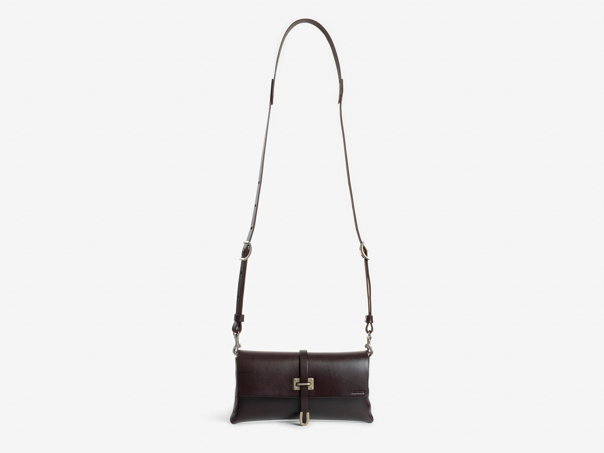 A dark brown leather crossbody bag with a rectangular shape, adjustable shoulder strap, and a gold-tone buckle closure on the front flap, displayed against a white background.
