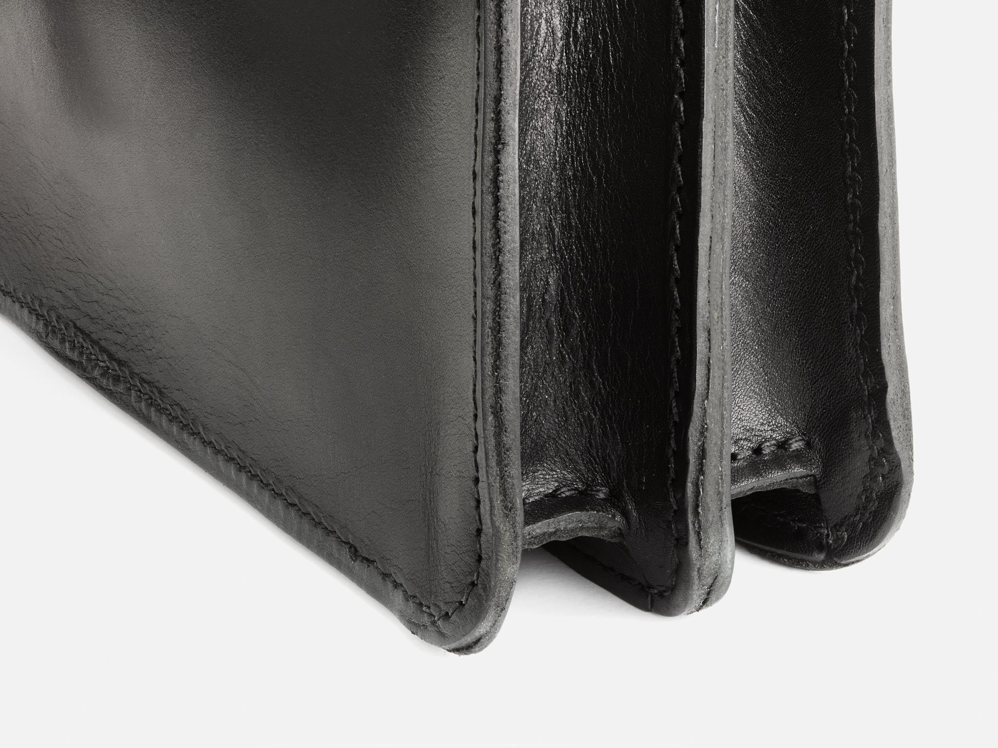 Close-up of the corner and interior sections of a black leather wallet, showing detailed stitching and smooth texture.