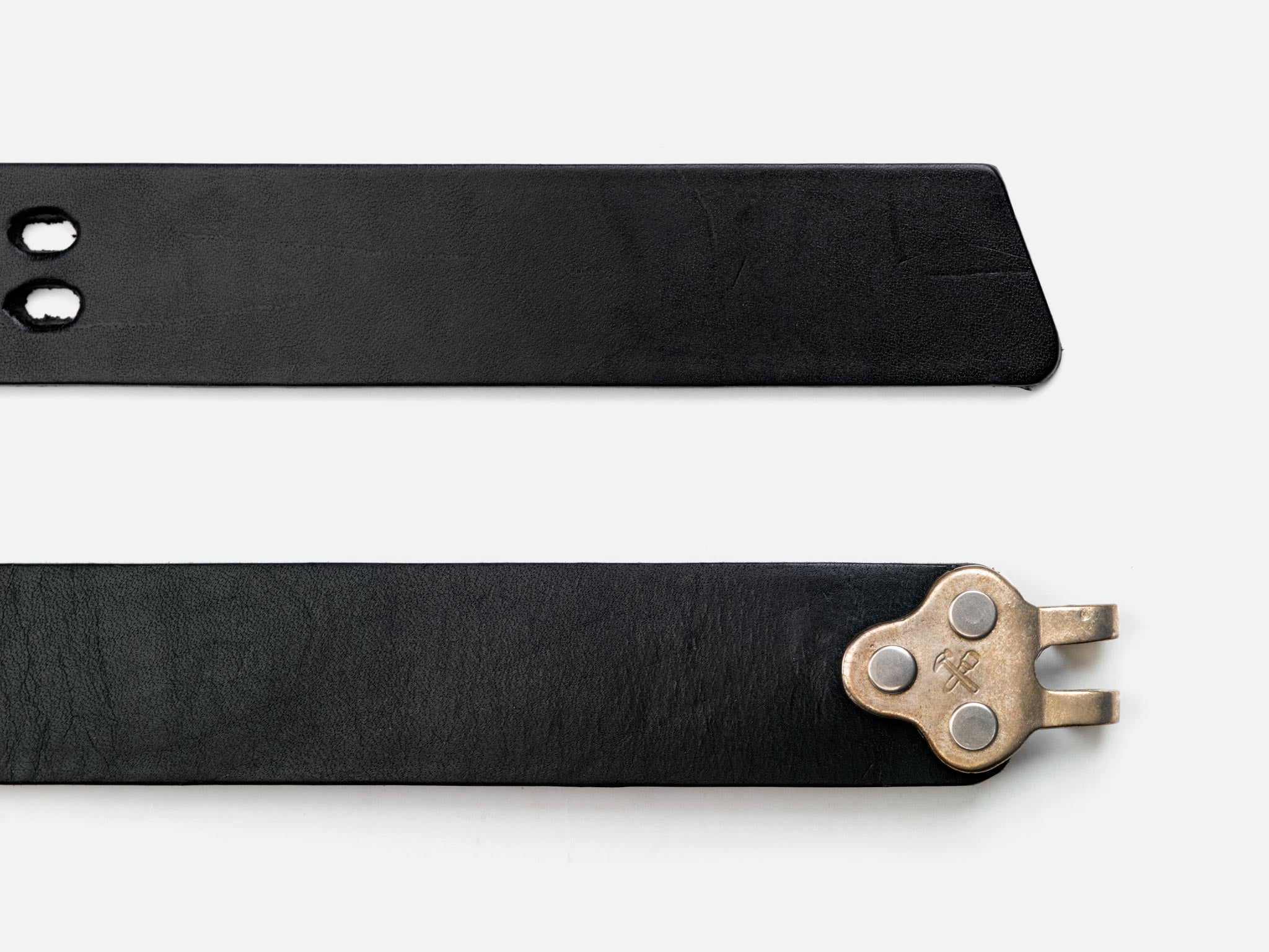 Two black leather belt ends on a white background; one end has two holes, while the other end features a unique metallic clasp with three rivets and a pronged hook.