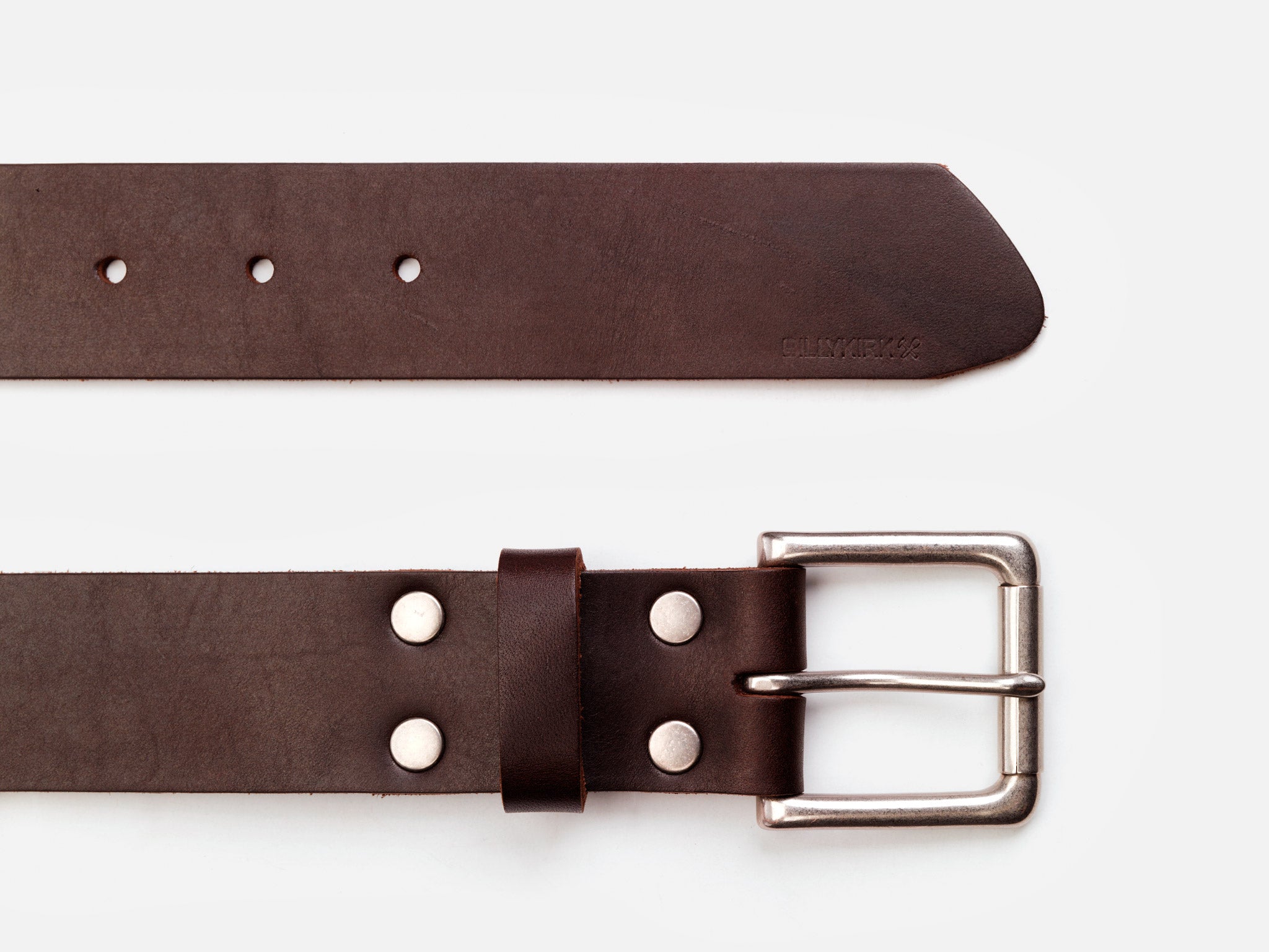 A brown leather belt with a silver buckle and metal rivets is shown laid flat on a white background. The belt end is pointed, and several adjustment holes are visible.