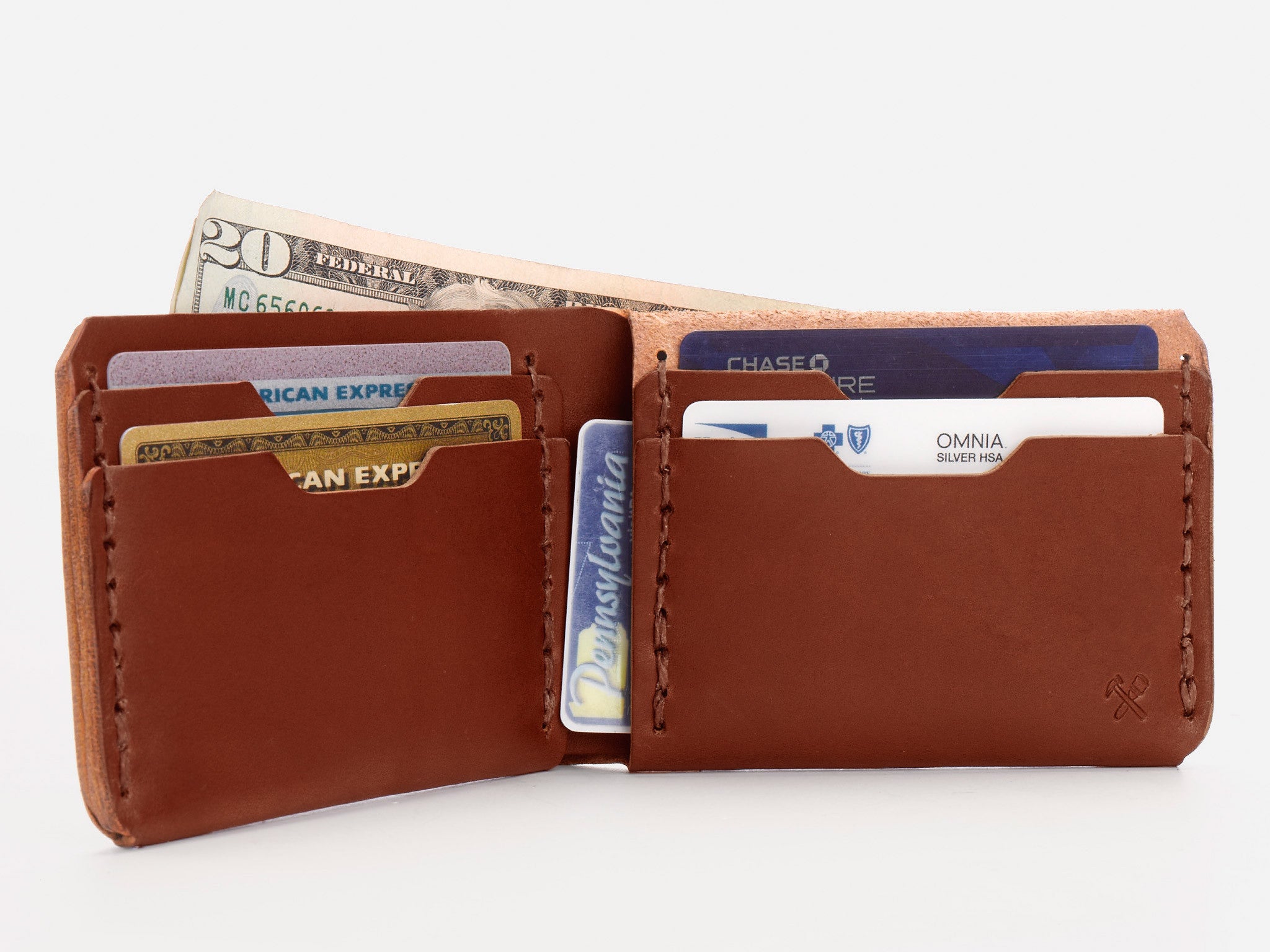 A brown leather wallet open to display several credit cards and IDs in its slots, with a twenty-dollar bill partially visible in the cash compartment.